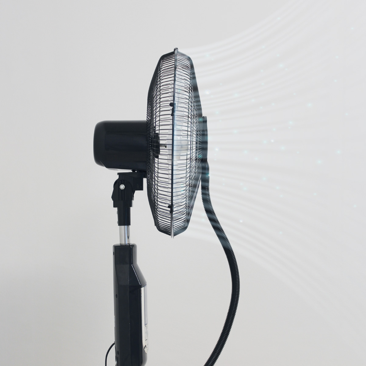 Ventilador eléctrico negro soplando aire. El ventilador está sobre un fondo blanco.