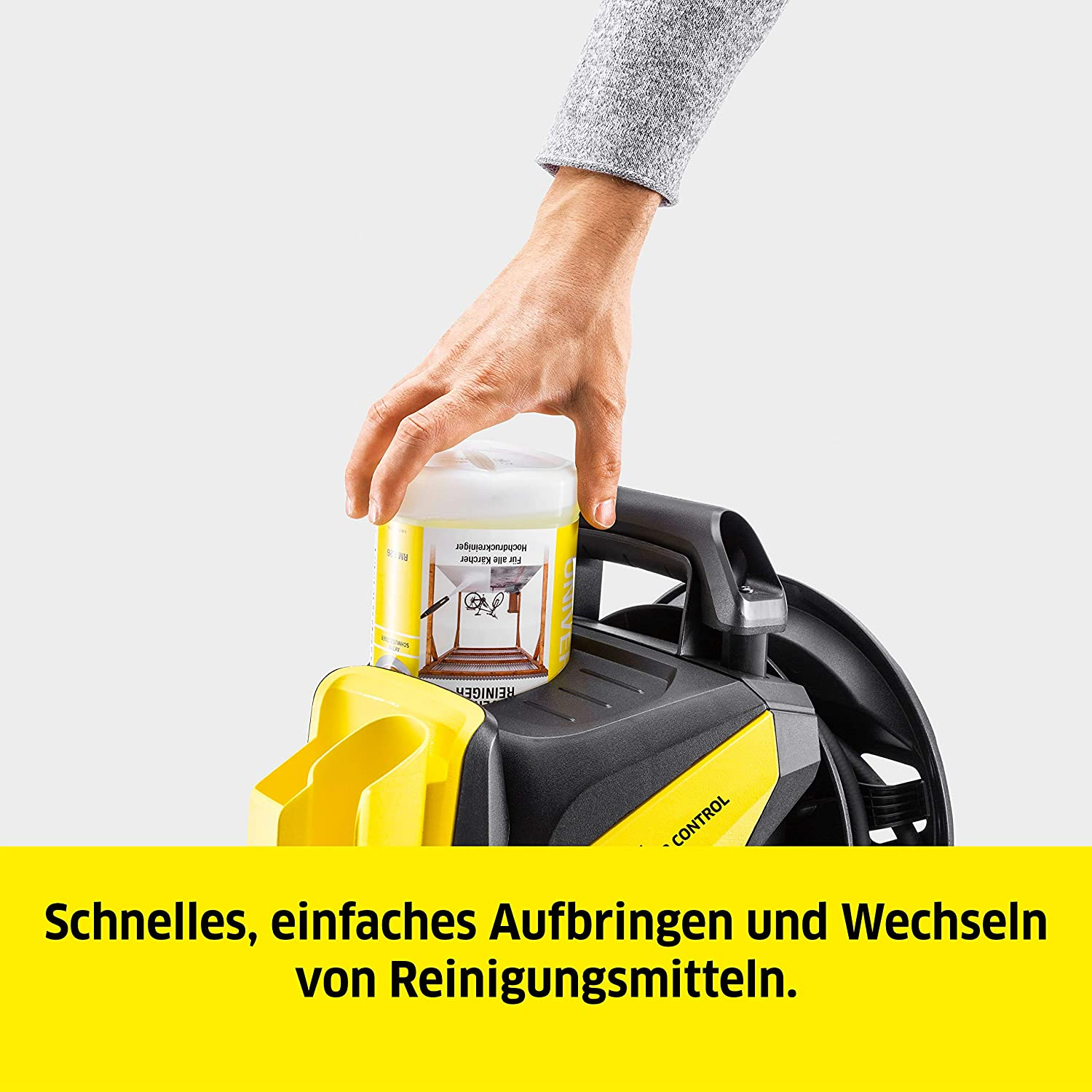 Eine Hand gießt Reinigungslösung in einen gelb-schwarzen Hochdruckreiniger. Text ist enthalten.