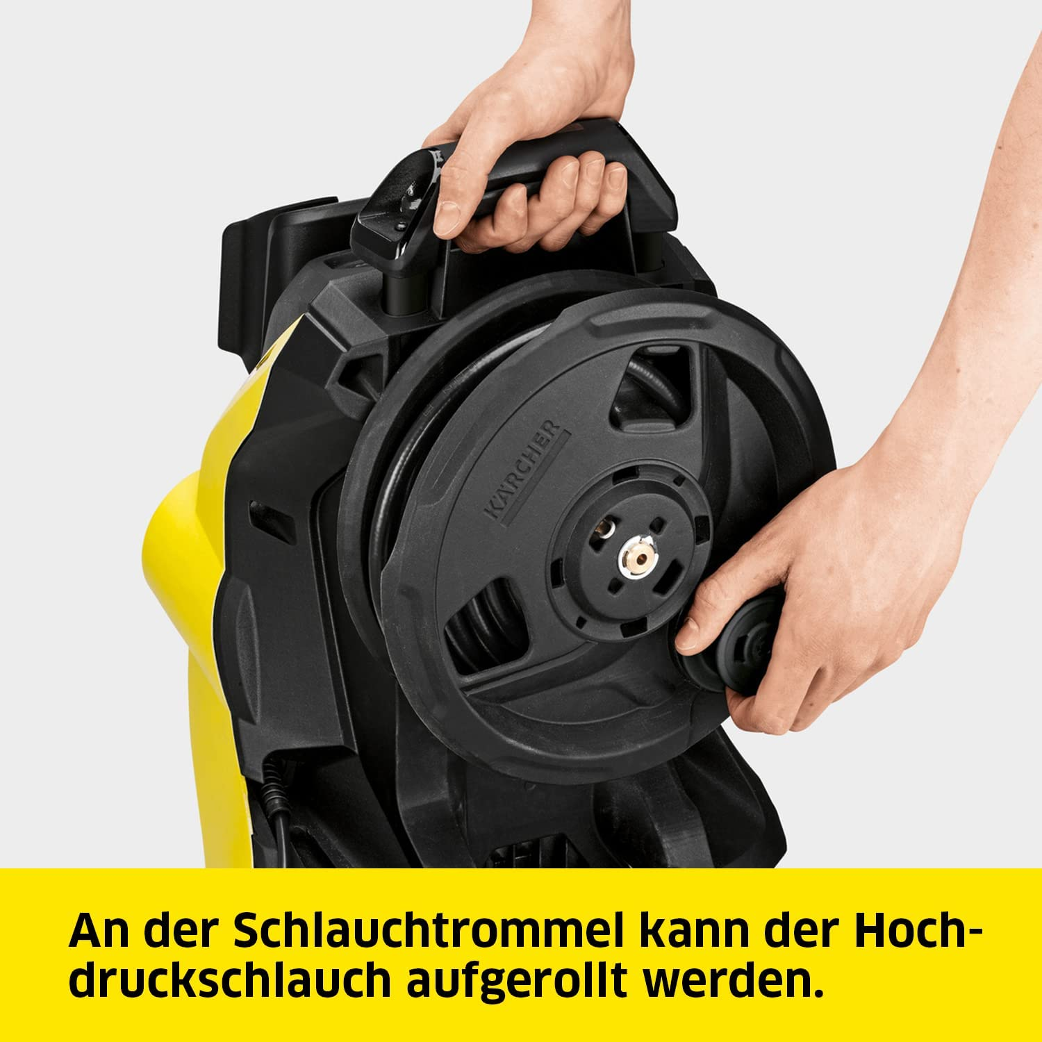 Eine Person hält eine gelbe Hochdruckreiniger-Schlauchtrommel. Weißer Hintergrund.