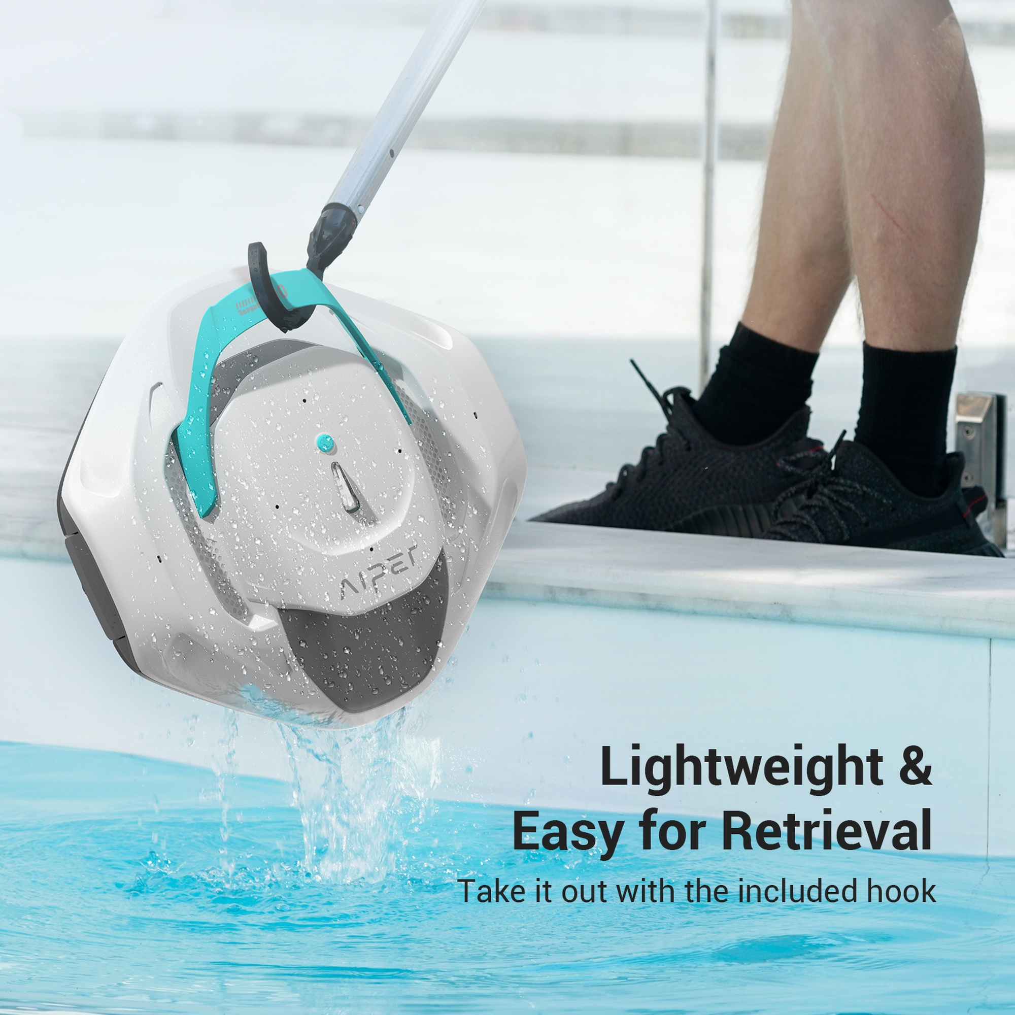 Un pulitore per piscina viene recuperato da una piscina con un gancio. Il pulitore è bianco e turchese.