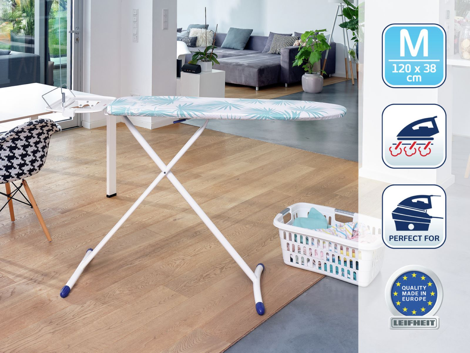 Tabla de planchar con estampado de hojas. El fondo incluye una sala de estar con sofá y cesta.