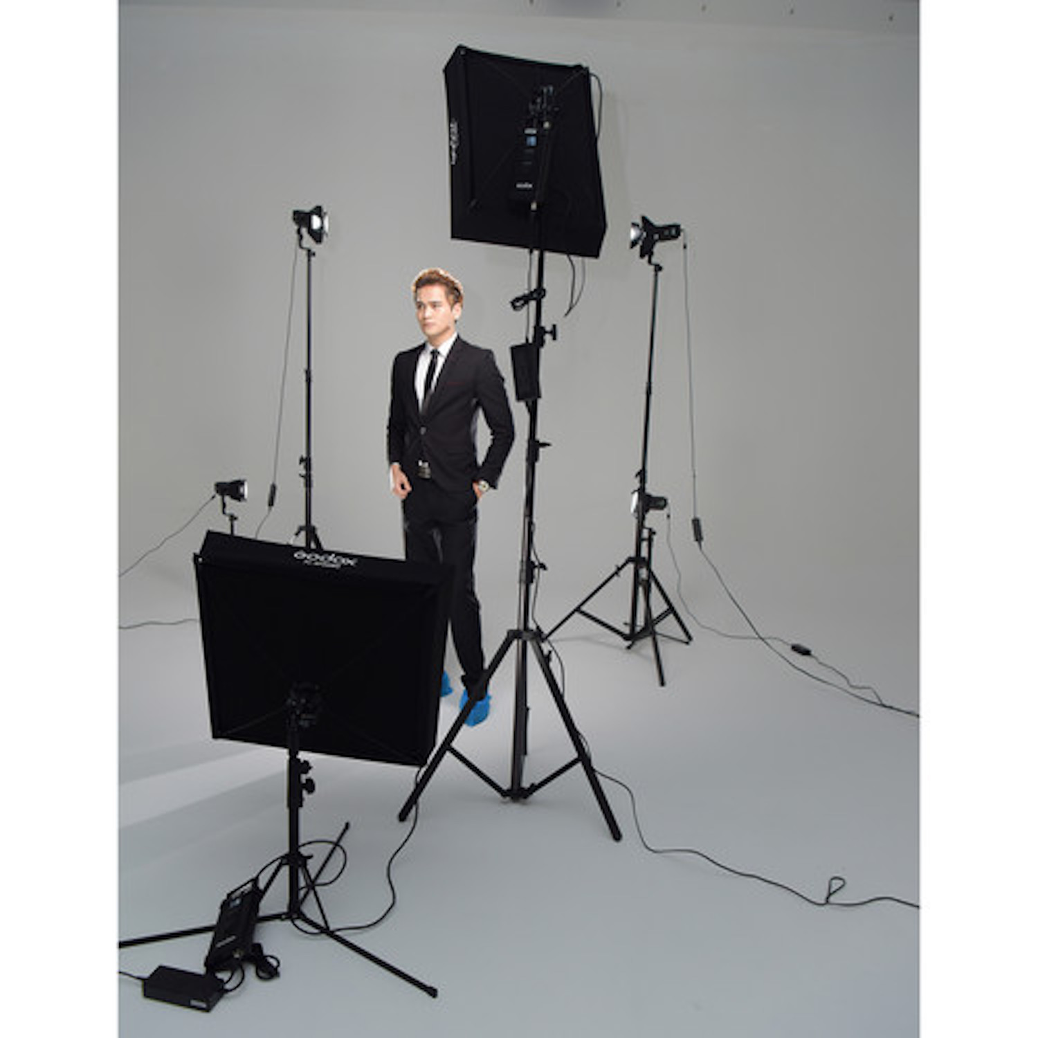 Mann im Anzug posiert in einem Studio mit Fotoausrüstung und Lichtern.