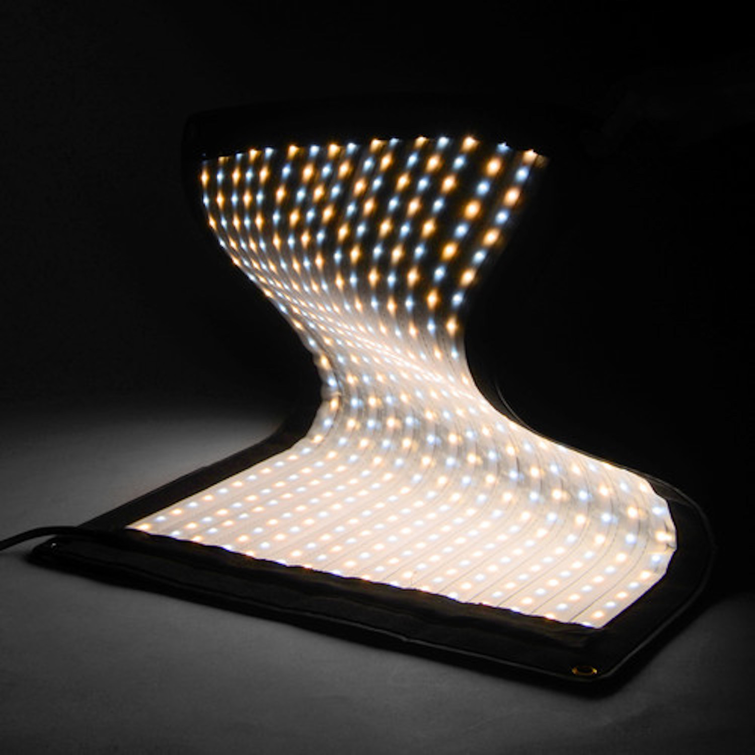 Flexibles LED-Panel mit weißen und gelben Lichtern. Es hat eine gebogene Form vor schwarzem Hintergrund.