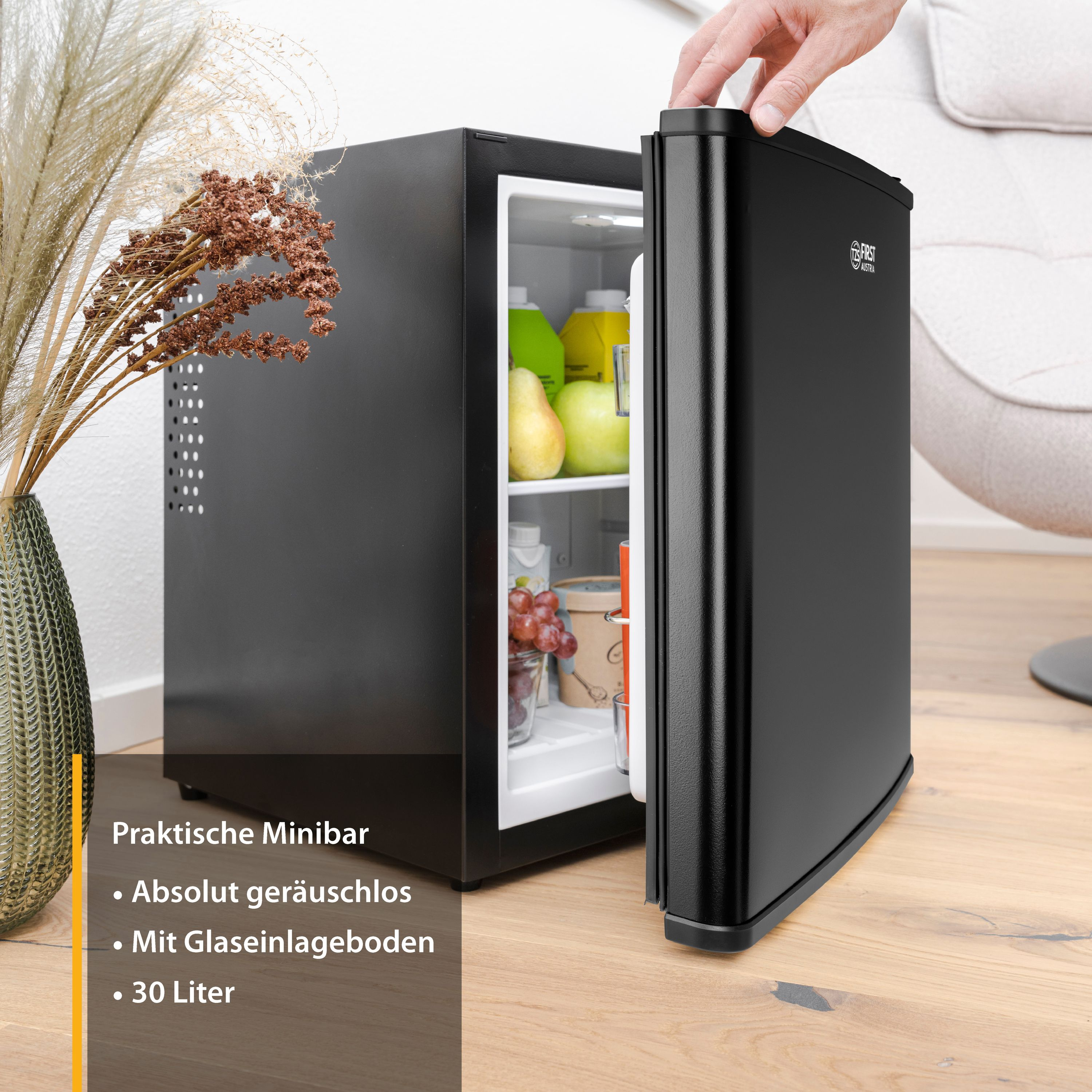 Un mini frigo nero con la porta aperta, che rivela frutta e bevande all'interno.