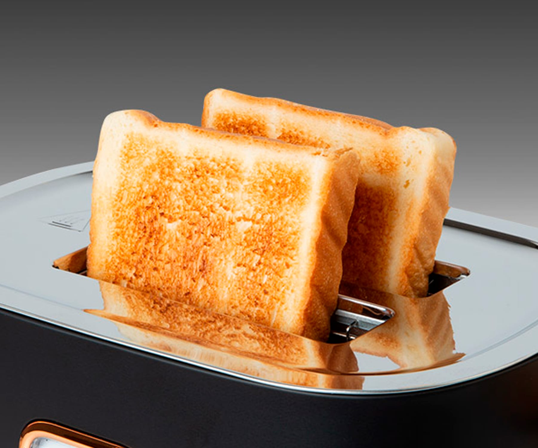 Tostowane kromki chleba w tosterze, z szarym tłem.