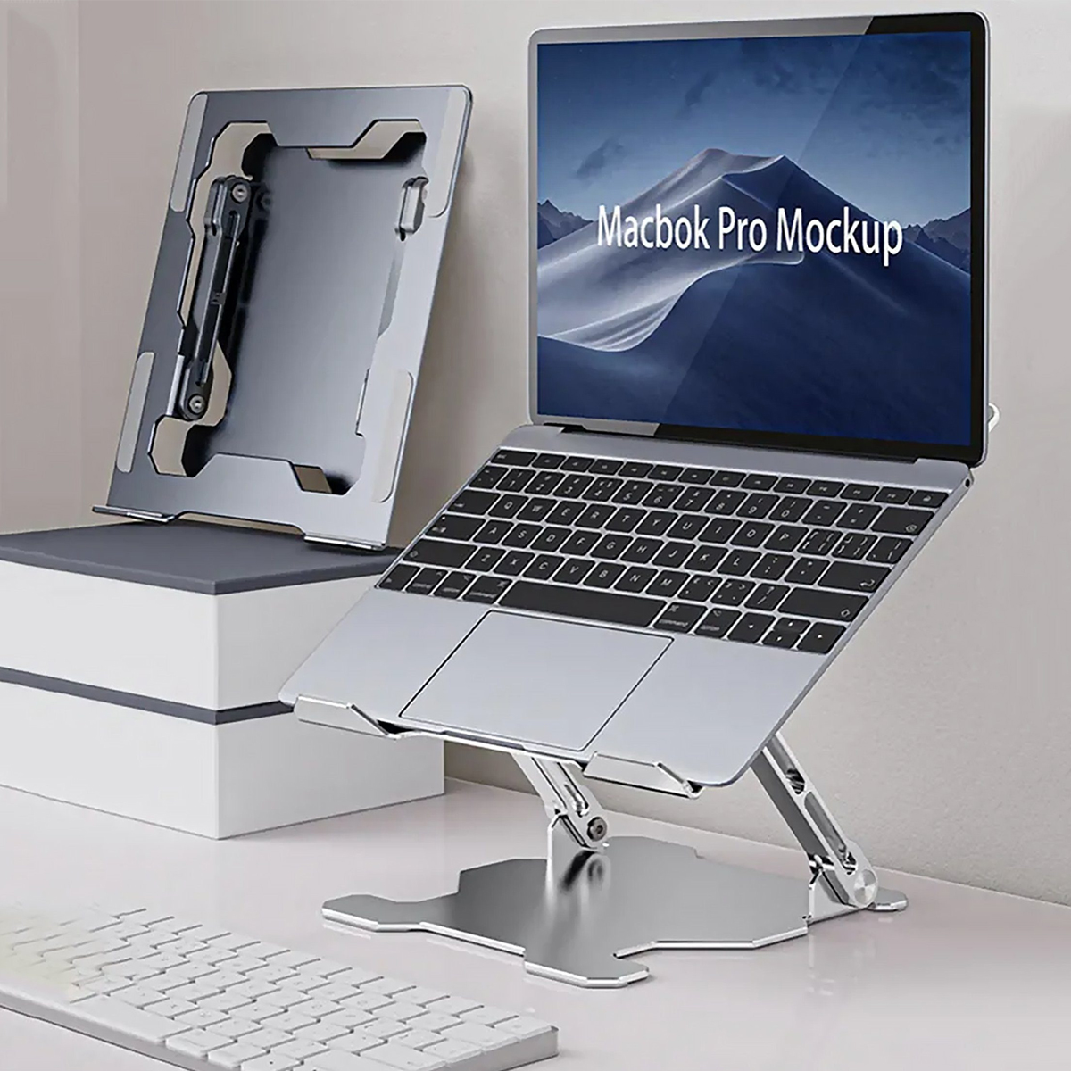 Laptop auf einem silbernen Ständer. Zusätzlicher Ständer links. Tastatur im Vordergrund. Weißer Hintergrund.