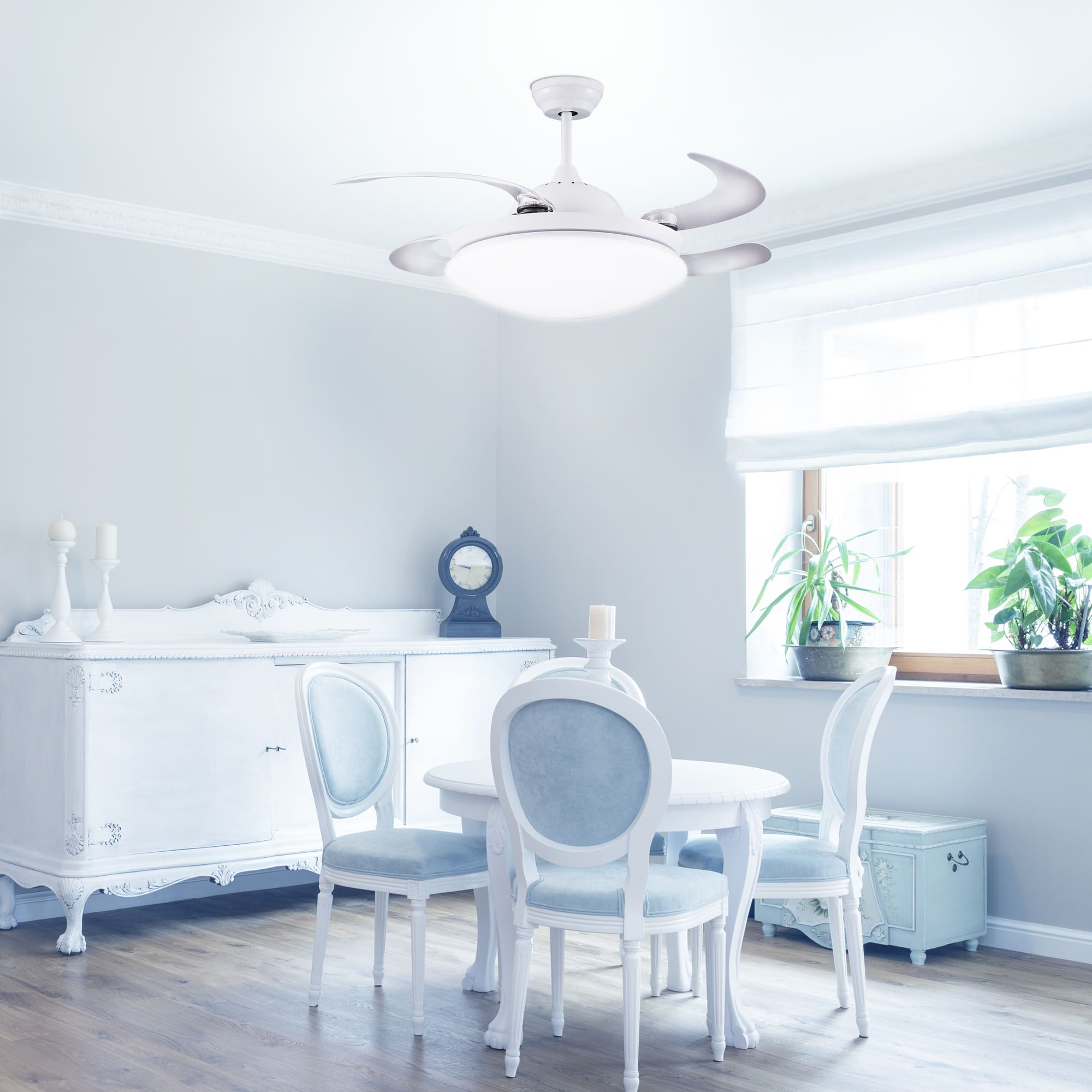 Comedor con muebles blancos y sillas azul claro. Hay un ventilador de techo.