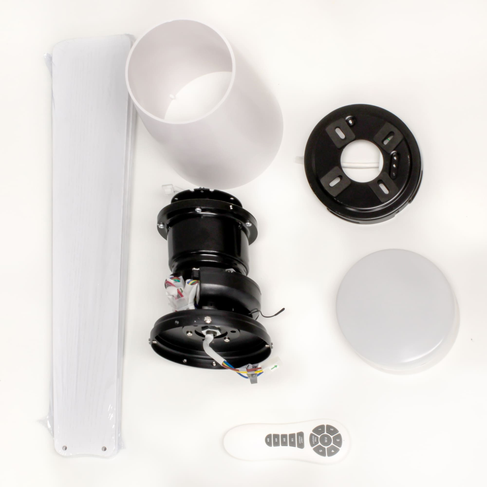 Componentes de ventilador de techo blanco desmontados sobre una superficie blanca.