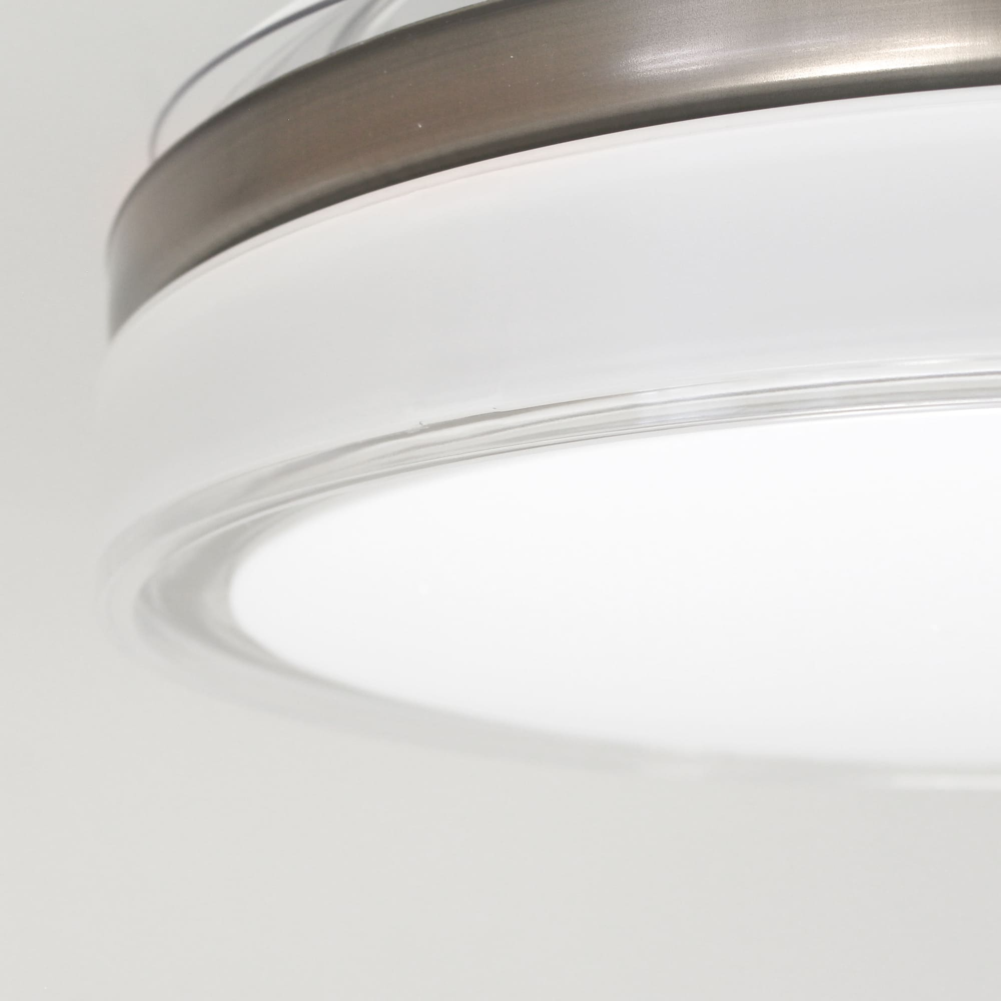 Primer plano de una moderna lámpara de techo blanca con borde plateado y luz brillante y difusa.
