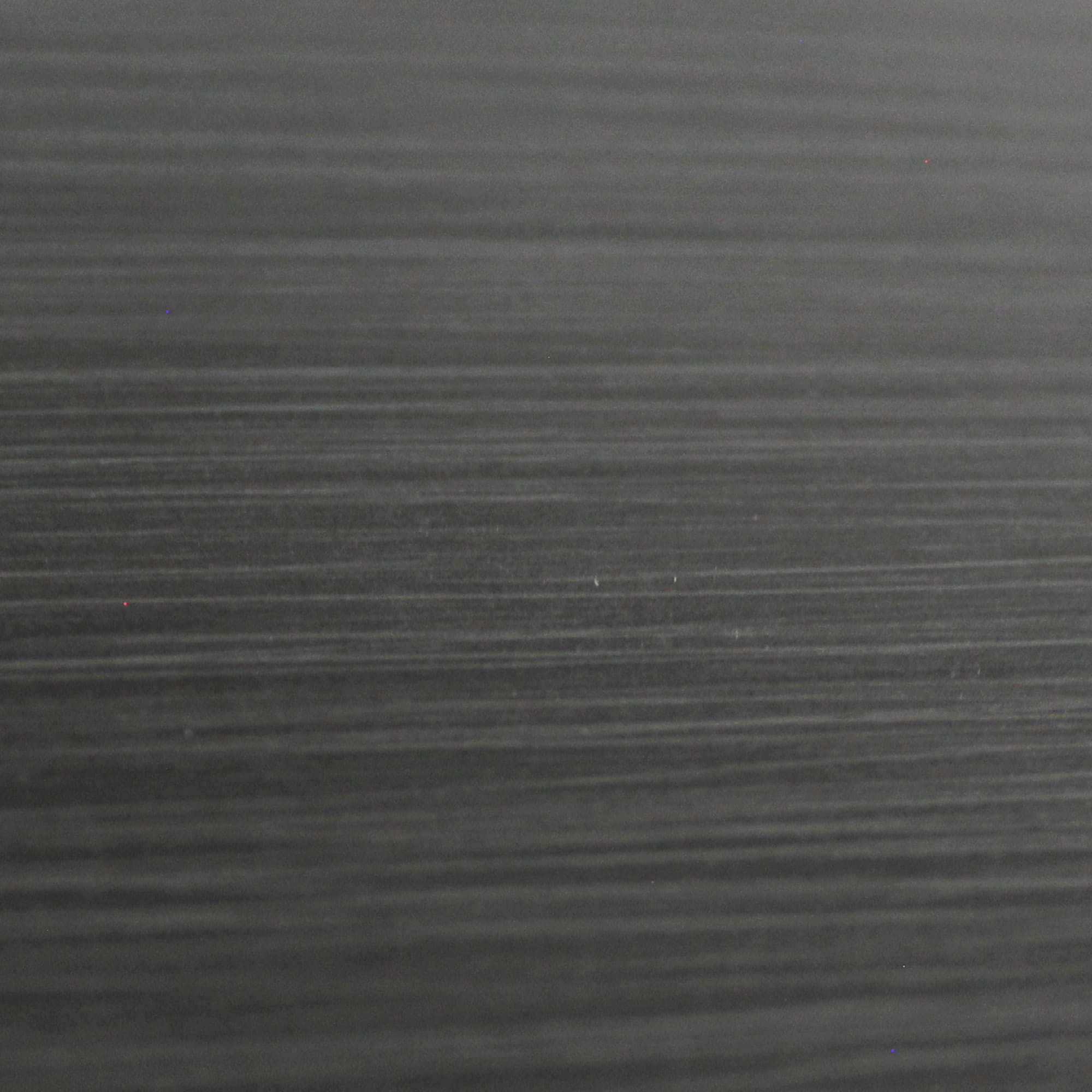 Primer plano de una superficie de metal gris oscuro cepillado con vetas horizontales.