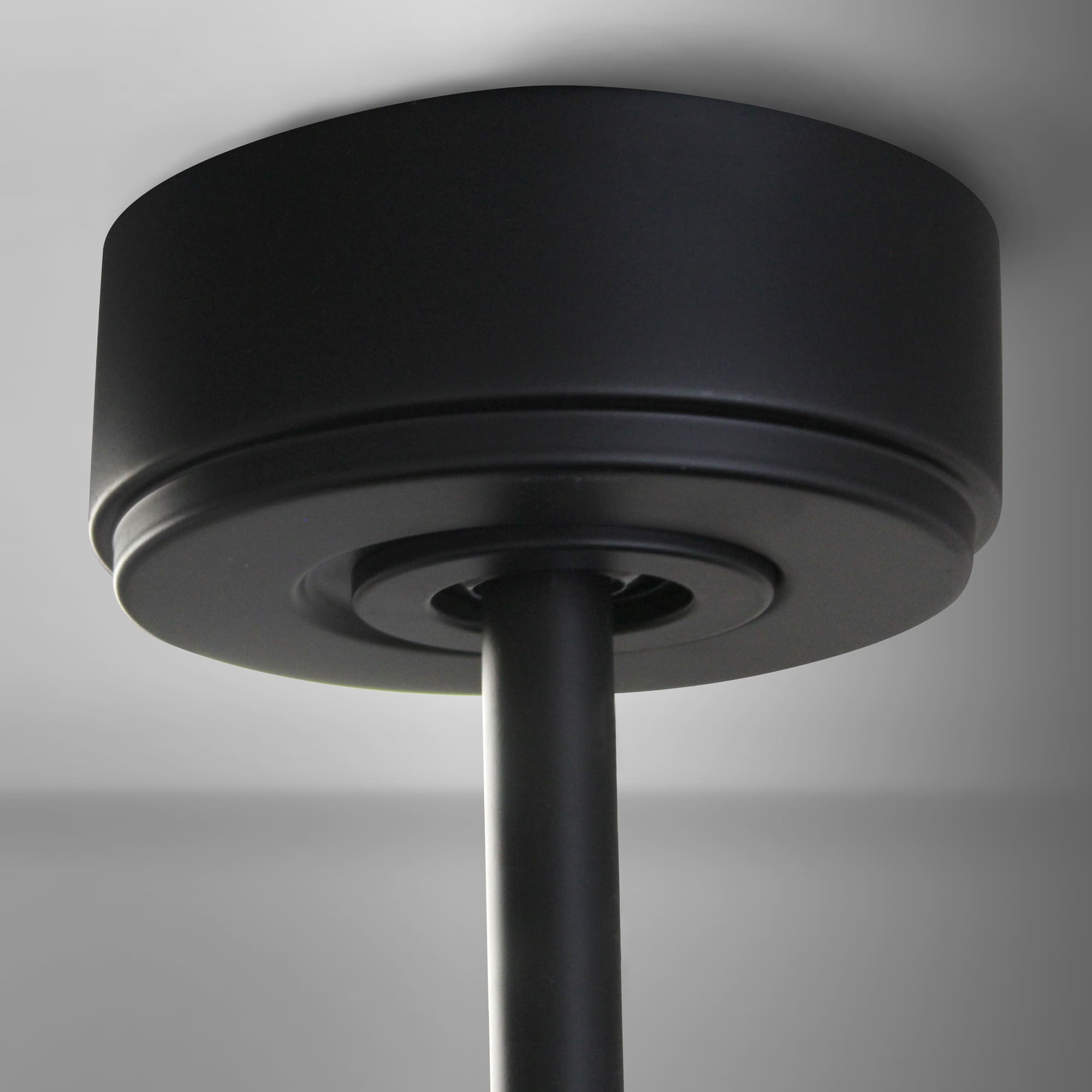 Soporte de ventilador de techo negro en un techo blanco, vista de cerca.