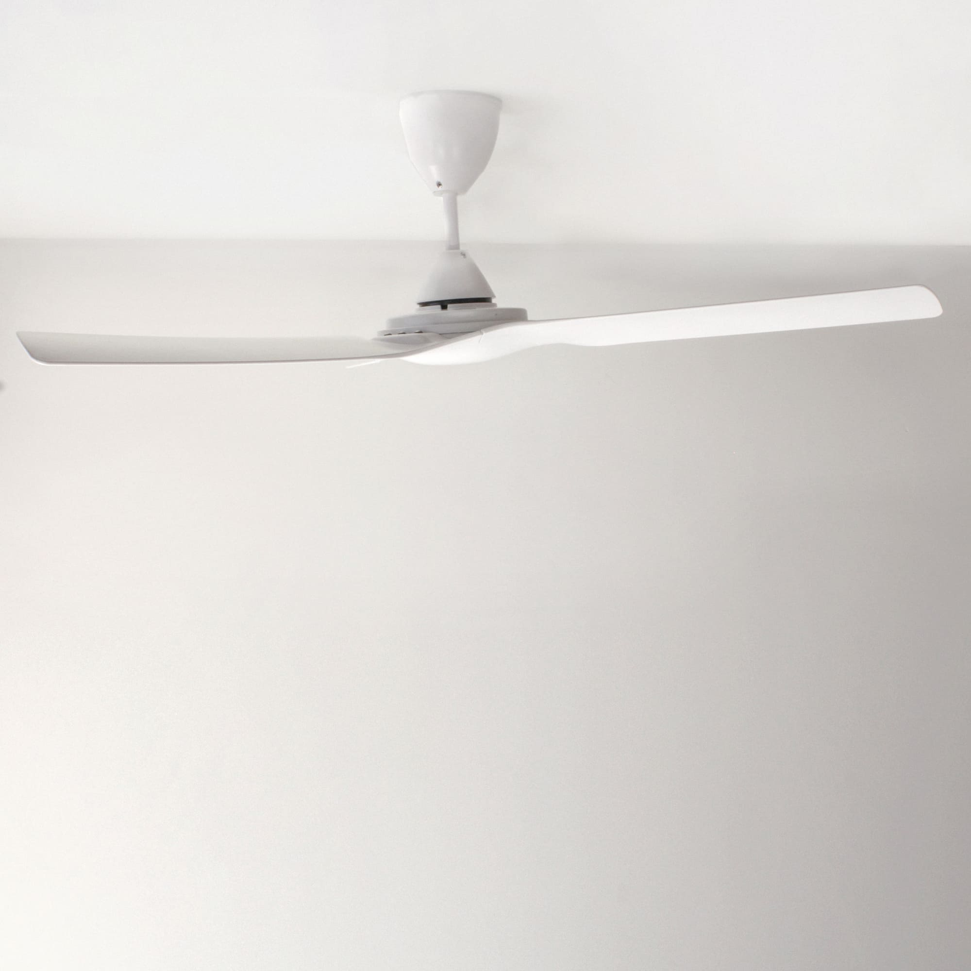 Un ventilador de techo blanco con dos aspas. El ventilador está montado en el techo.