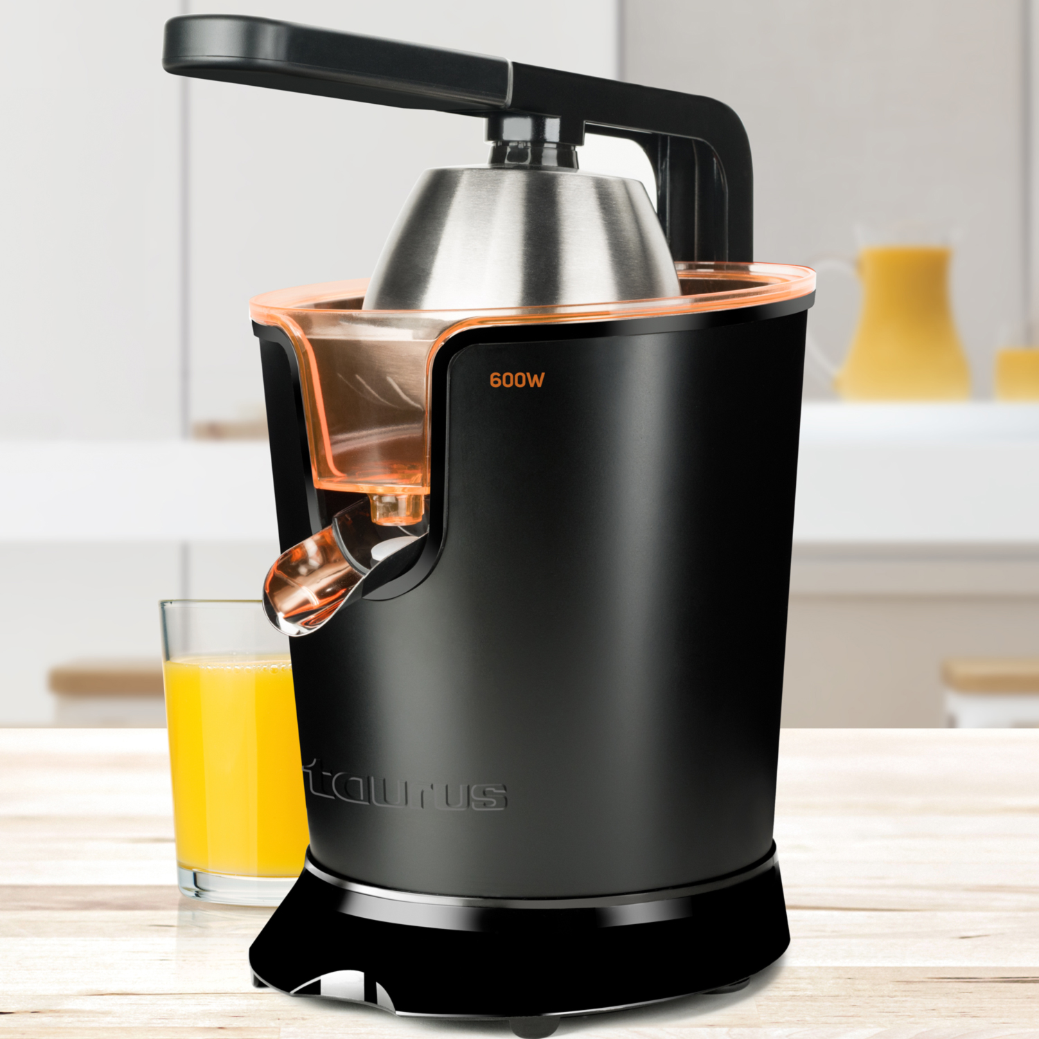 Una exprimidora negra y naranja con un vaso de zumo de naranja y un entorno de cocina.
