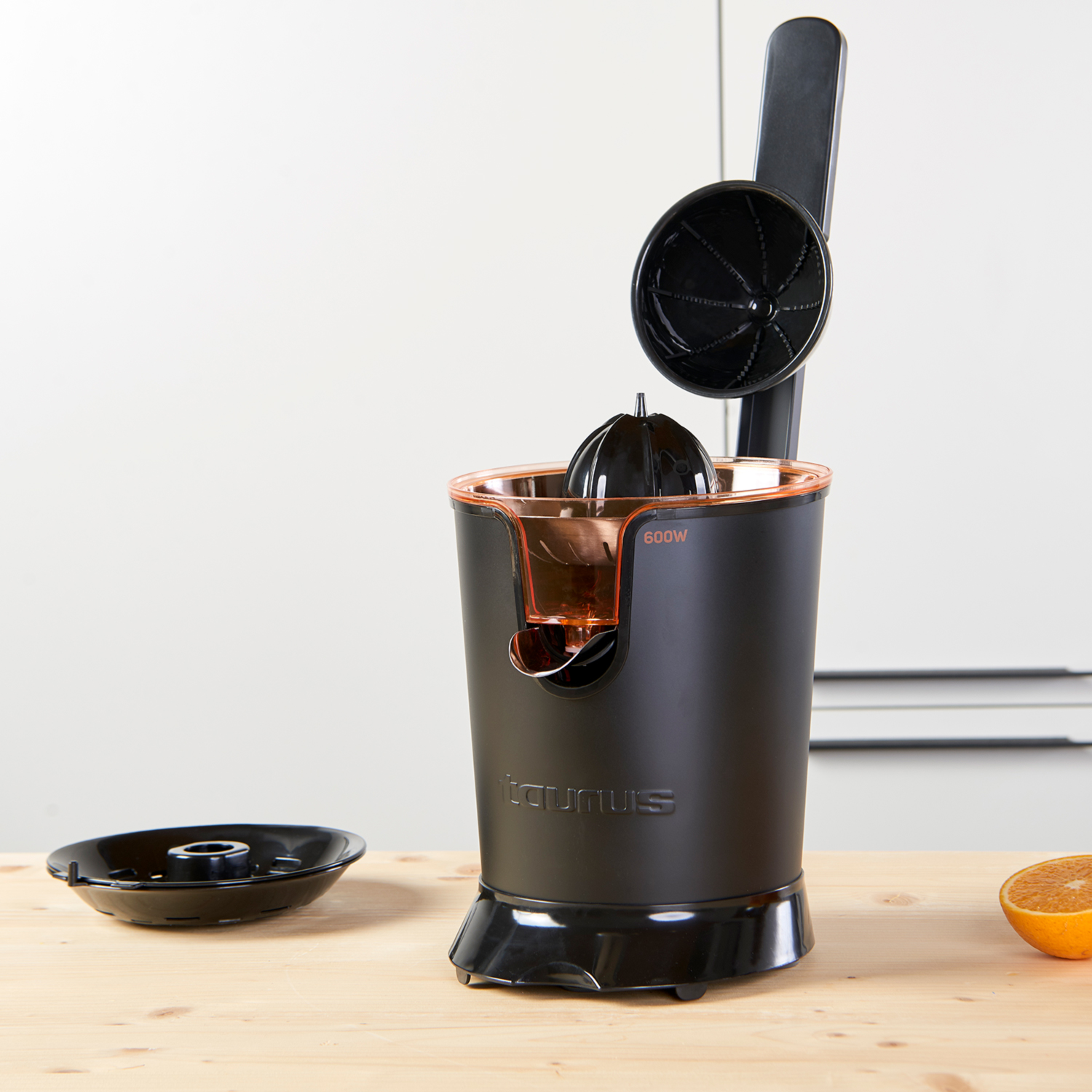 Exprimidor de cítricos negro y naranja con superficie de madera y media naranja.