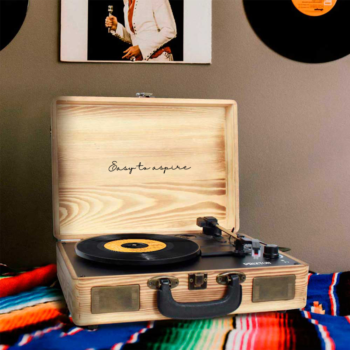 Gramofon w stylu vintage z tekstem "Easy to aspire" wewnątrz pokrywy. Białe tło.