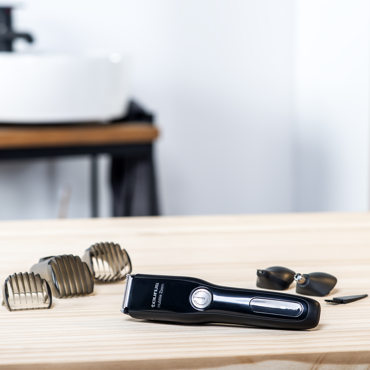 Una recortadora de barba negra y accesorios sobre una mesa de madera.