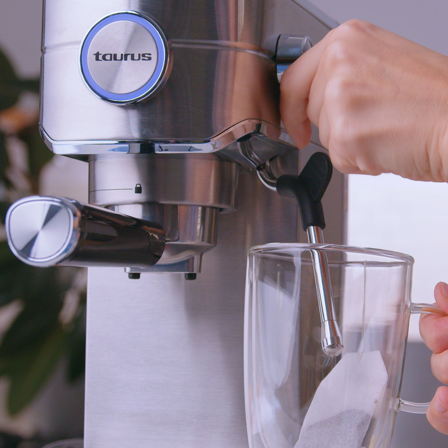 Máquina de espresso con una mano tirando de una palanca y un vaso de té.