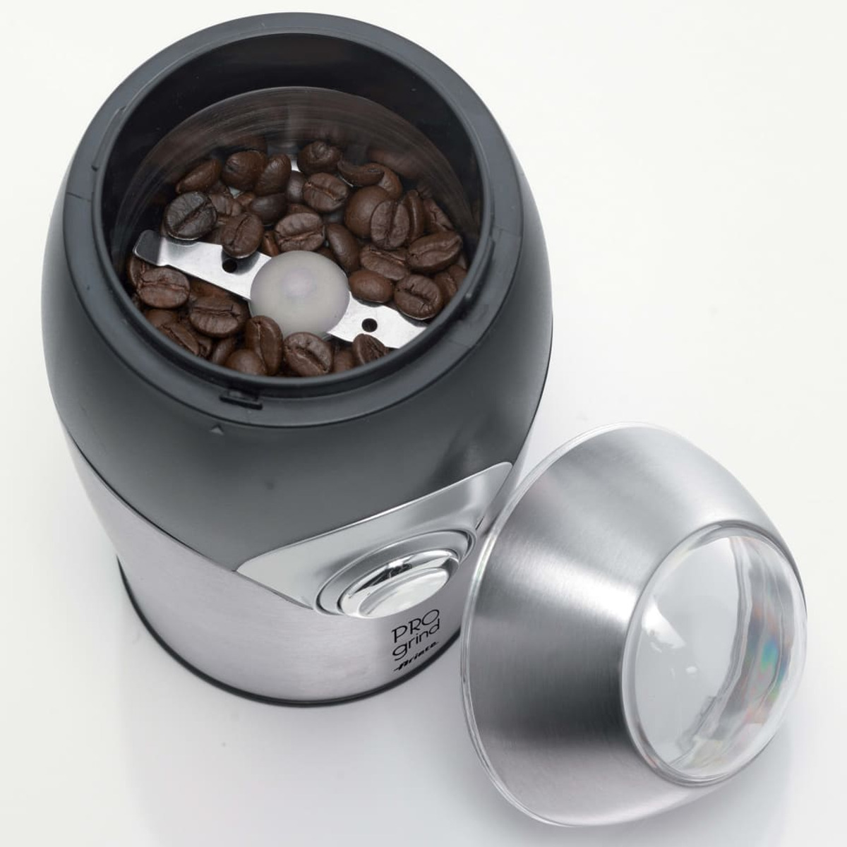 Kaffeemühle mit Kaffeebohnen und Klingen sichtbar. Schwarzes und silbernes Gehäuse, offener Deckel.