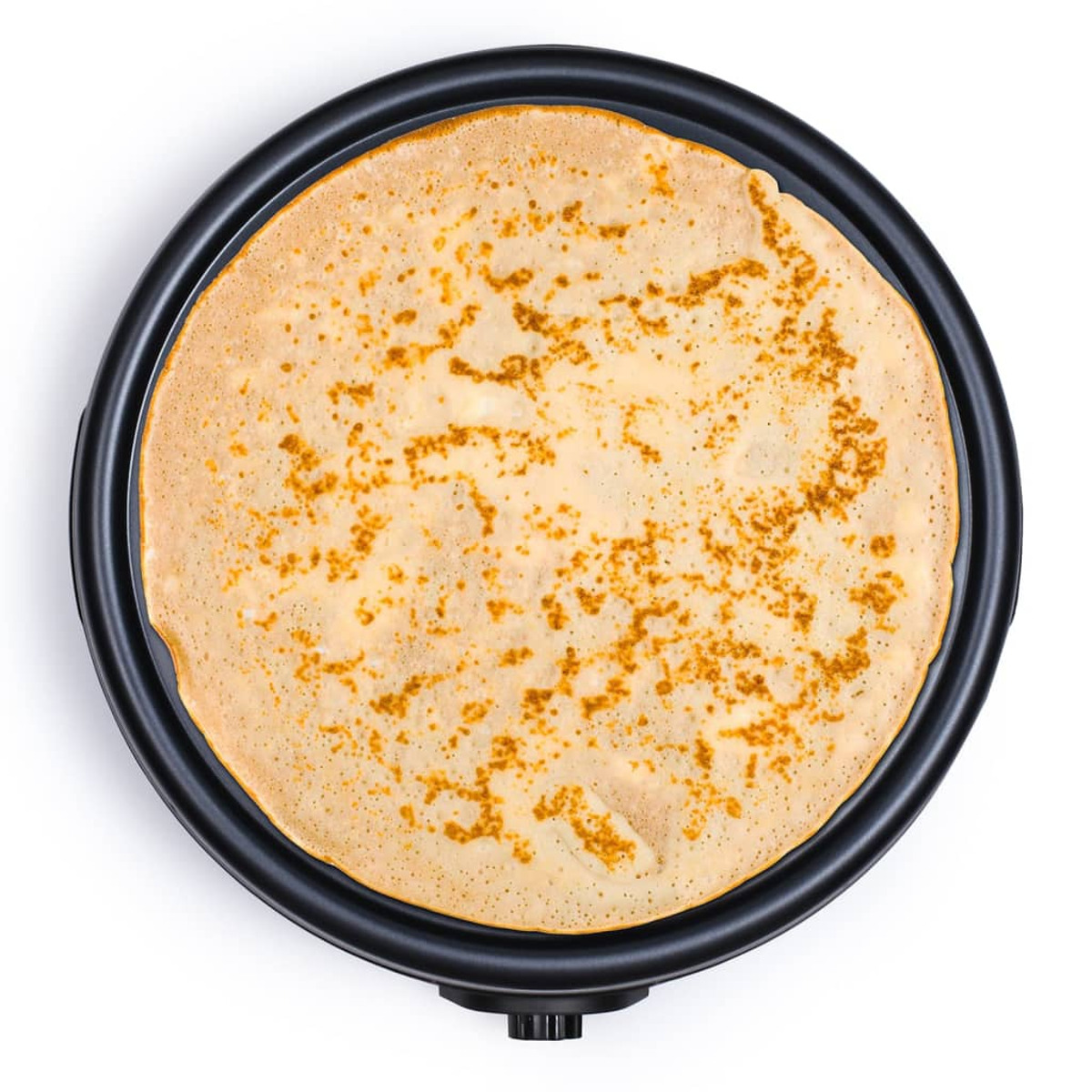 Pojedynczy naleśnik na czarnej patelni. Naleśnik jest złocistobrązowy.