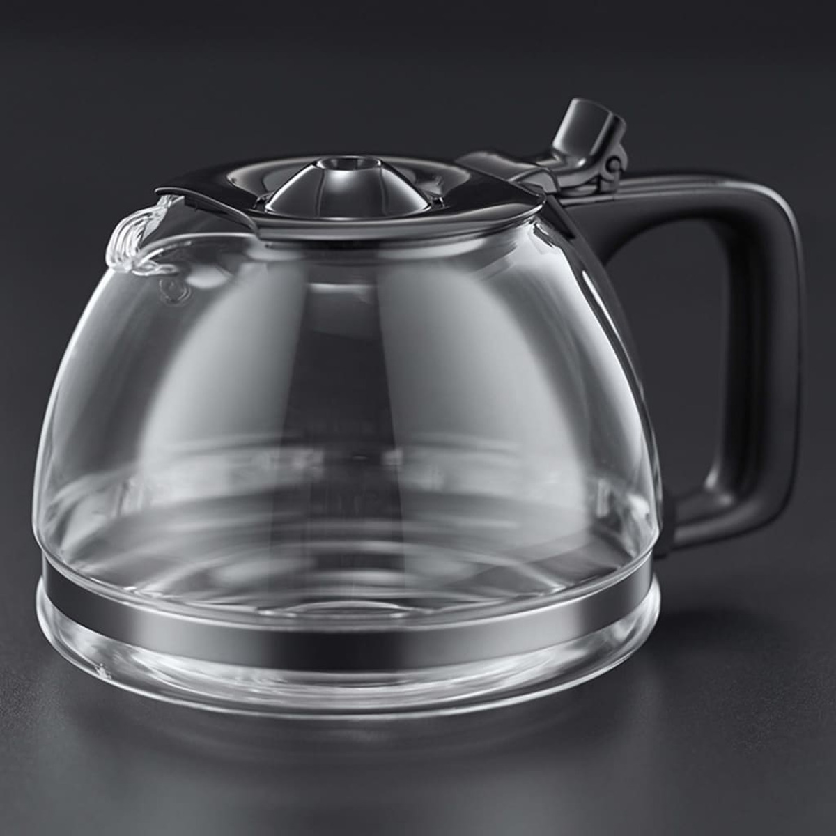 Szklana karafka do kawy z czarnym uchwytem i pokrywką, na ciemnym tle.