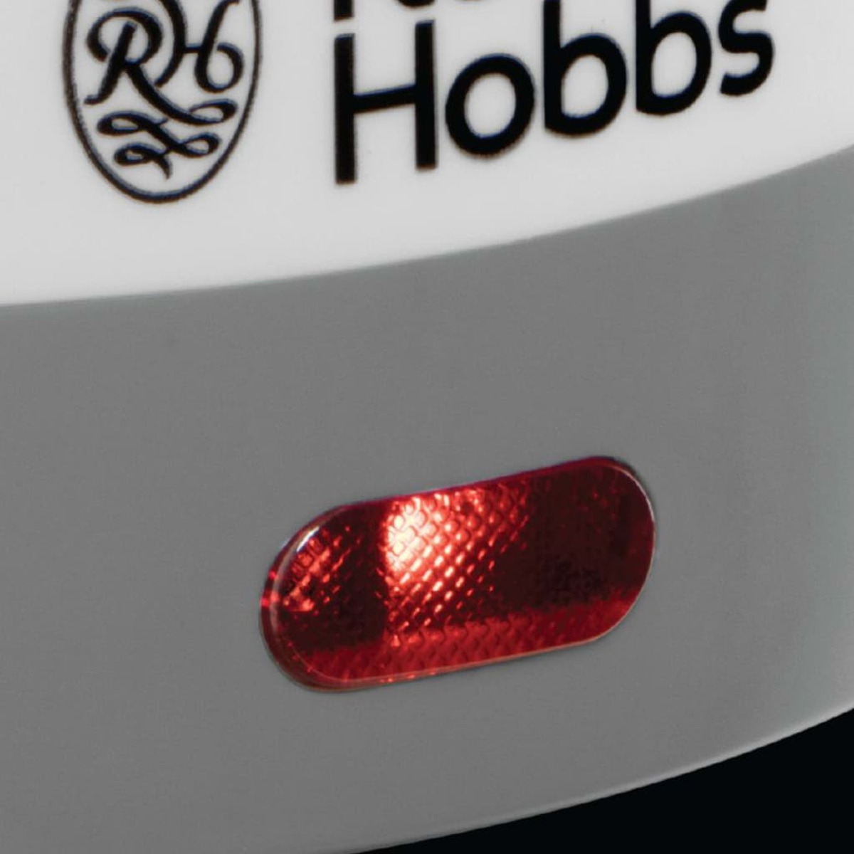 Zbliżenie czerwonej lampki kontrolnej zasilania na białym urządzeniu.