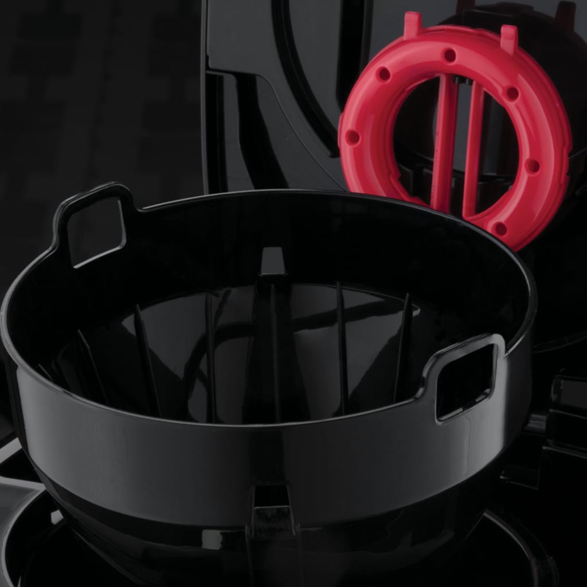 Czarne części ekspresu do kawy: filtr i czerwony pierścień. Ciemne tło.