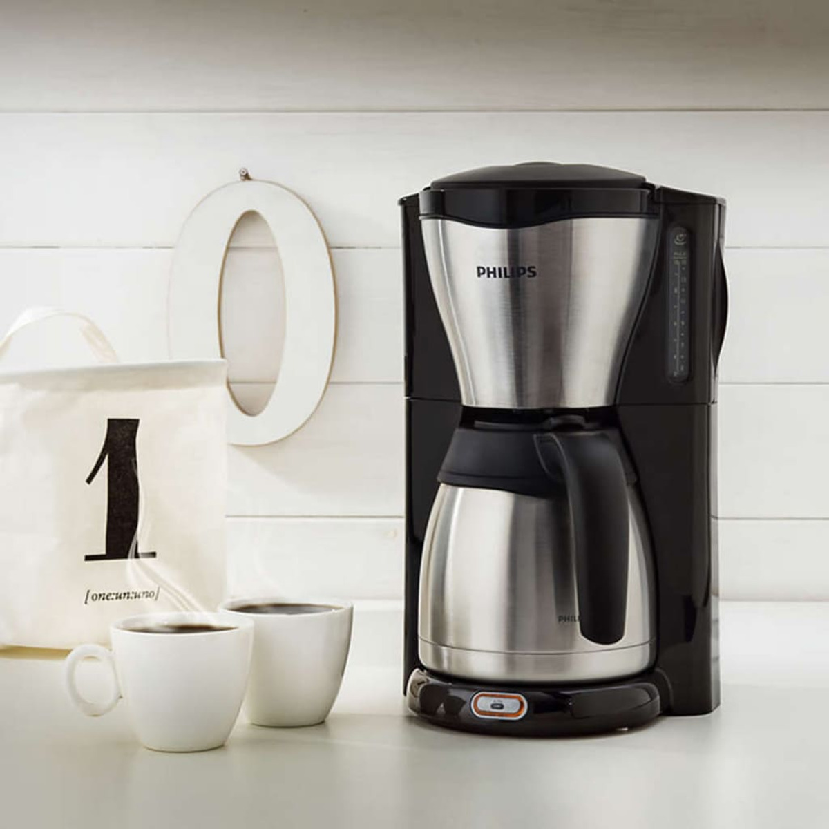 Macchina da caffè con tazze e una borsa con il numero 1. Sfondo bianco.