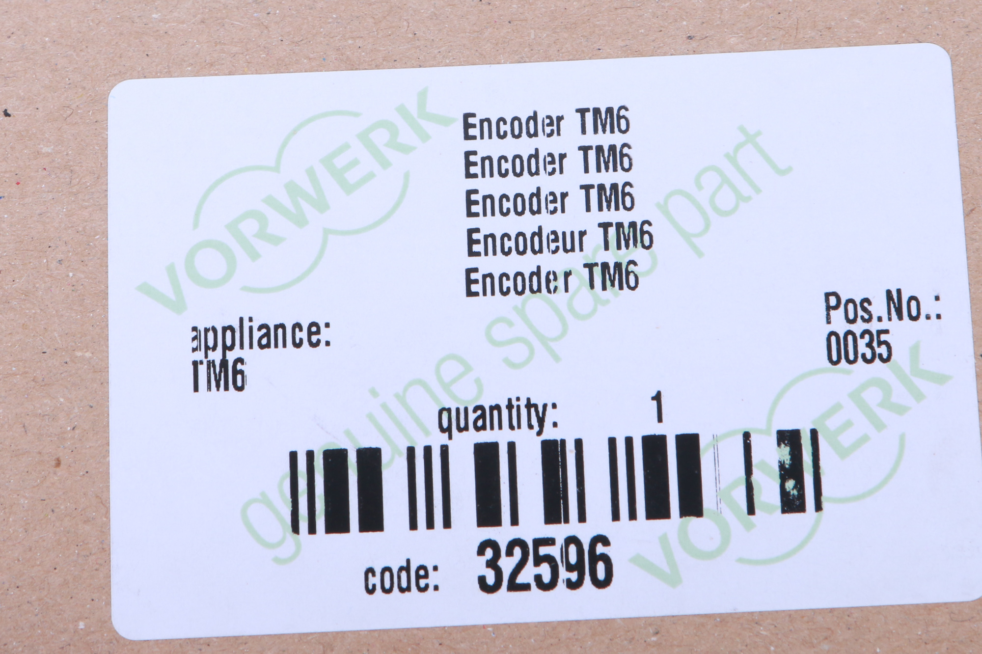 Ein Etikett mit dem sich wiederholenden Text 'Encoder TM6', Barcode und 'VORWERK'-Logo.