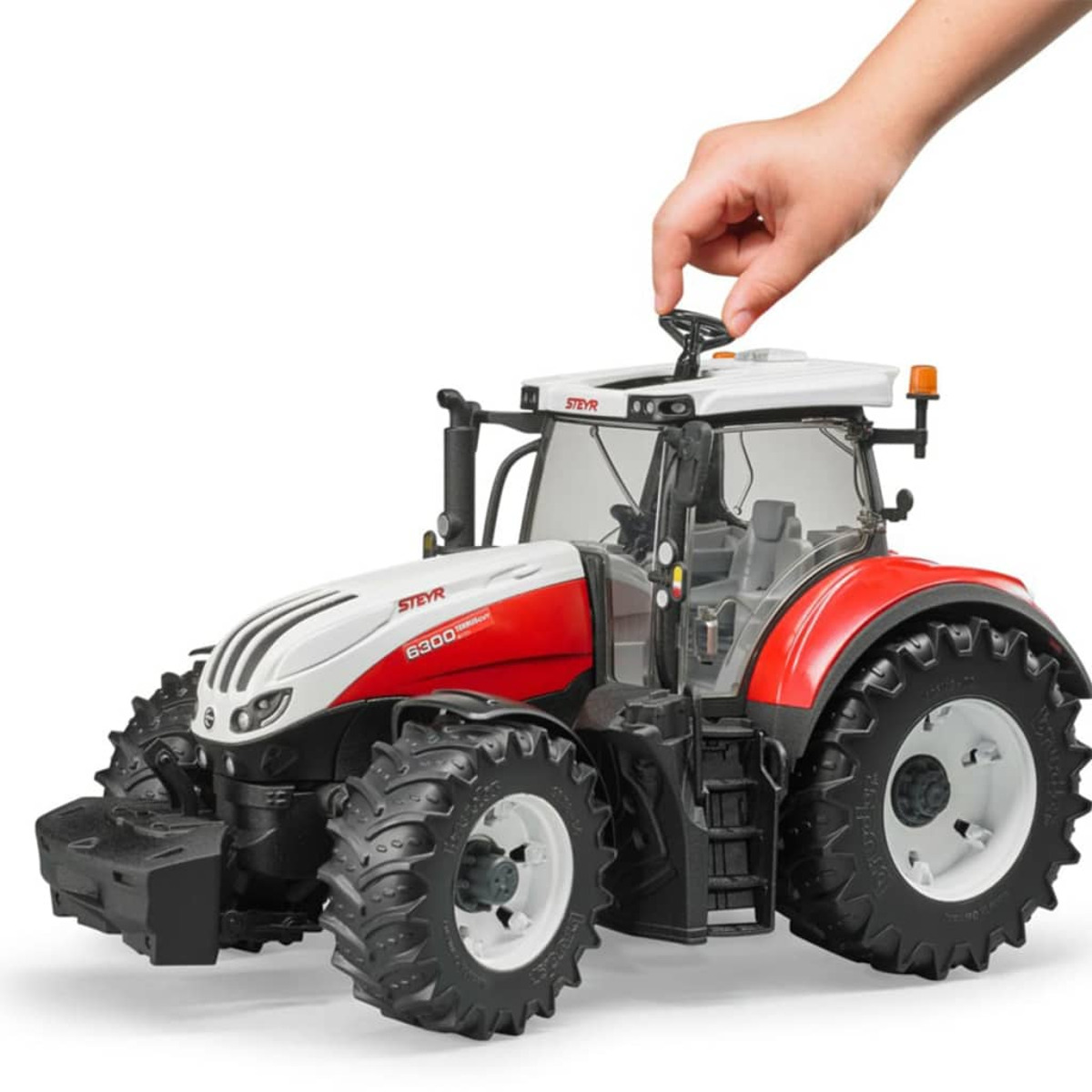 Biało-czerwony traktor, ręka dotyka kierownicy, białe tło. Steyr.