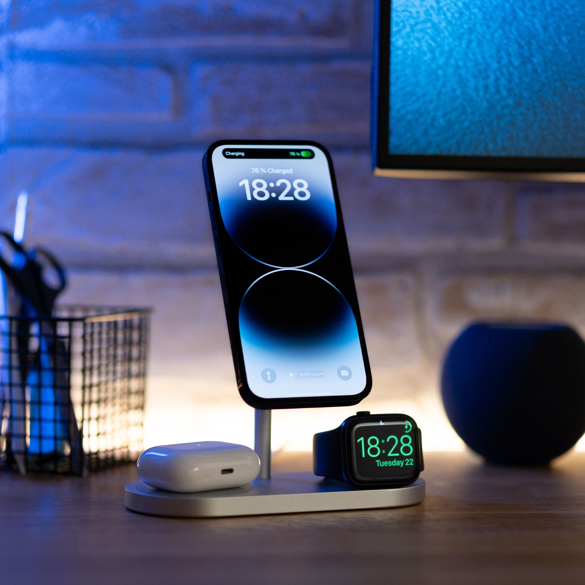 Stazione di ricarica con telefono, orologio e auricolari. Mostra ora e percentuale batteria.