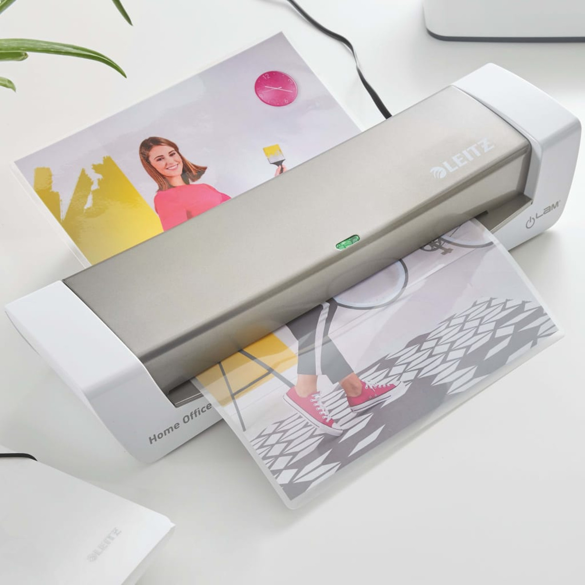 Laminator z obrazem kobiety laminowanym z innymi zdjęciami na biurku.