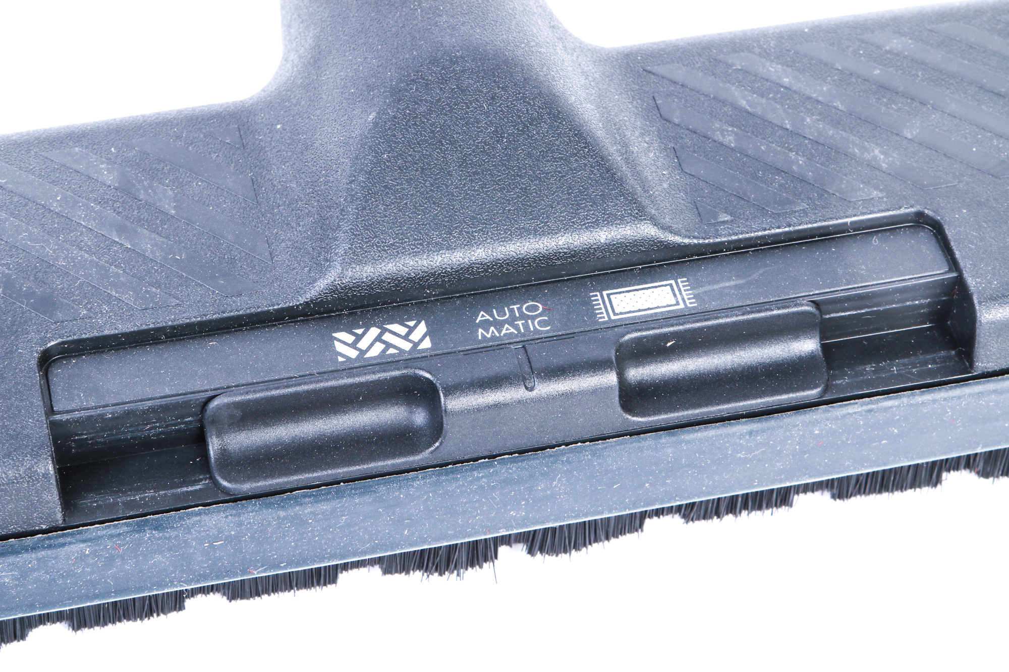 Nahaufnahme eines Staubsaugerkopfes mit 'Auto' und Akku-Symbol, schwarz und grau.
