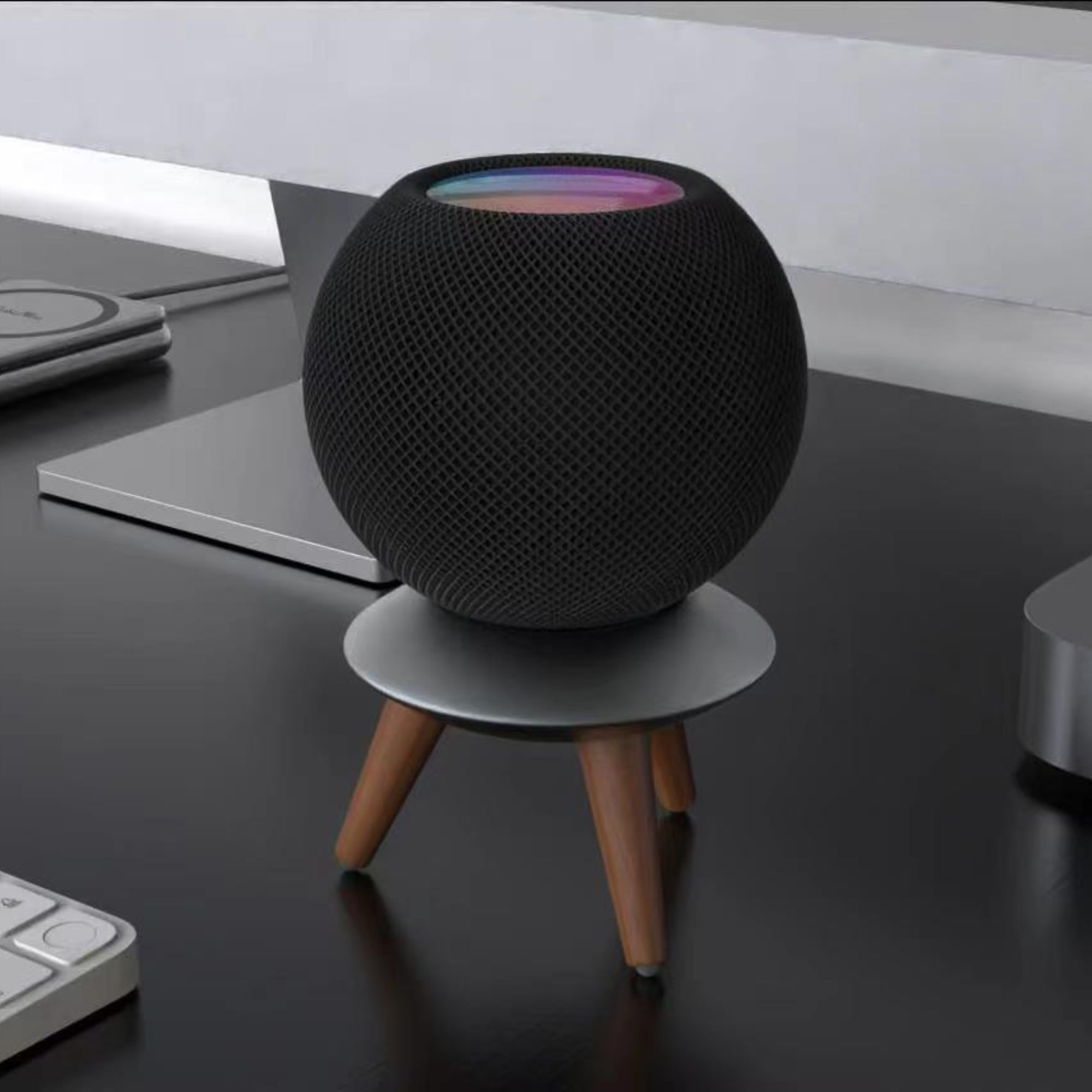 Schwarzer, kugelförmiger Smart Speaker auf einem kleinen silbernbeinigen Ständer.