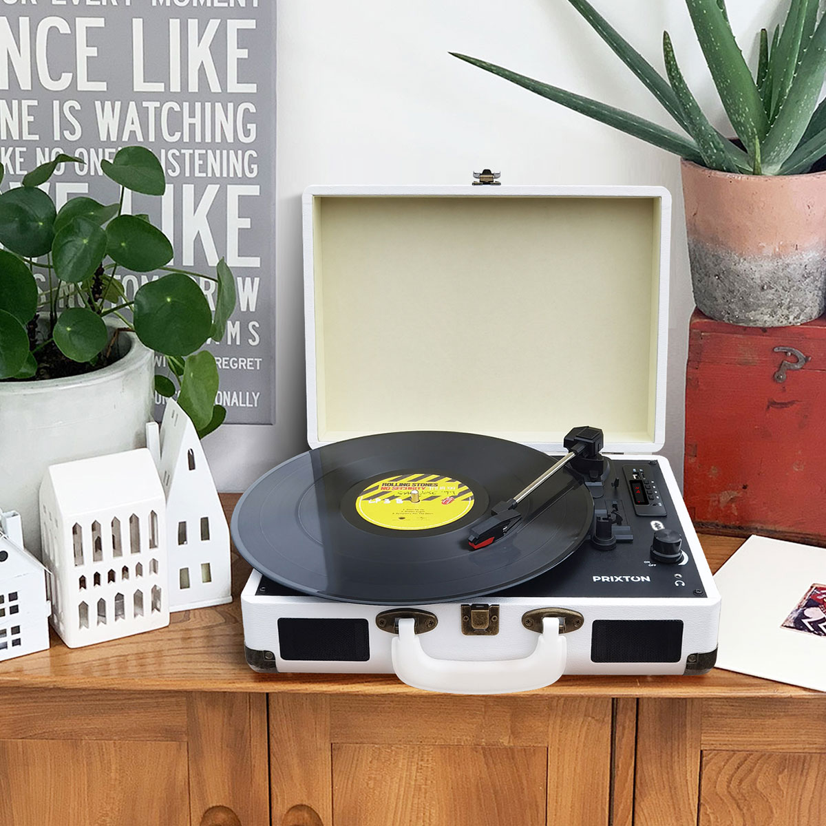 Zabytkowy gramofon z płytą winylową. Stoi na drewnianej szafce z dekoracjami.