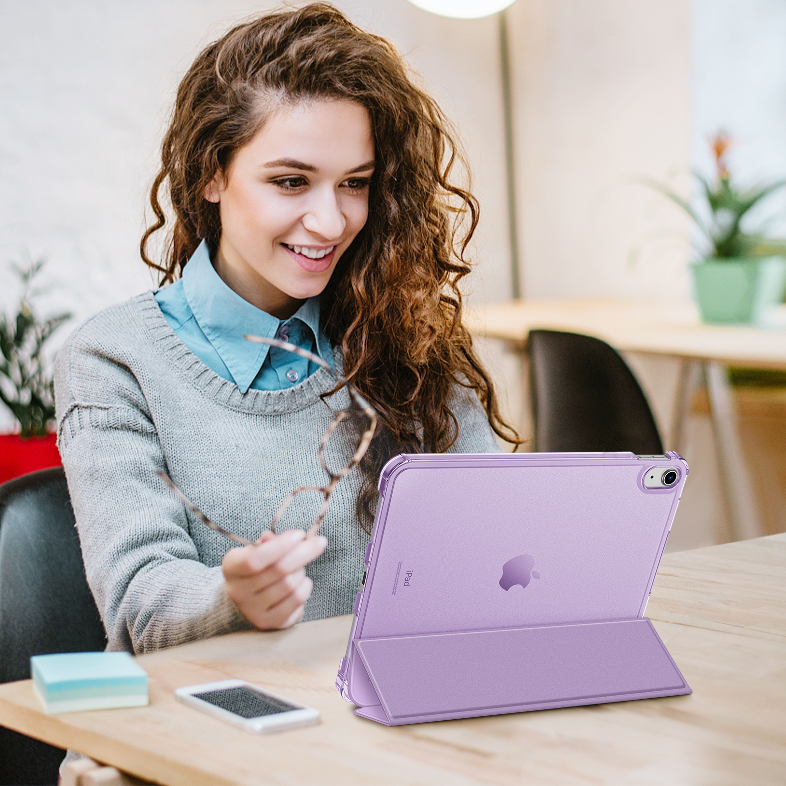 Frau hält Brille, lächelt, benutzt ein lila iPad in einem Case.