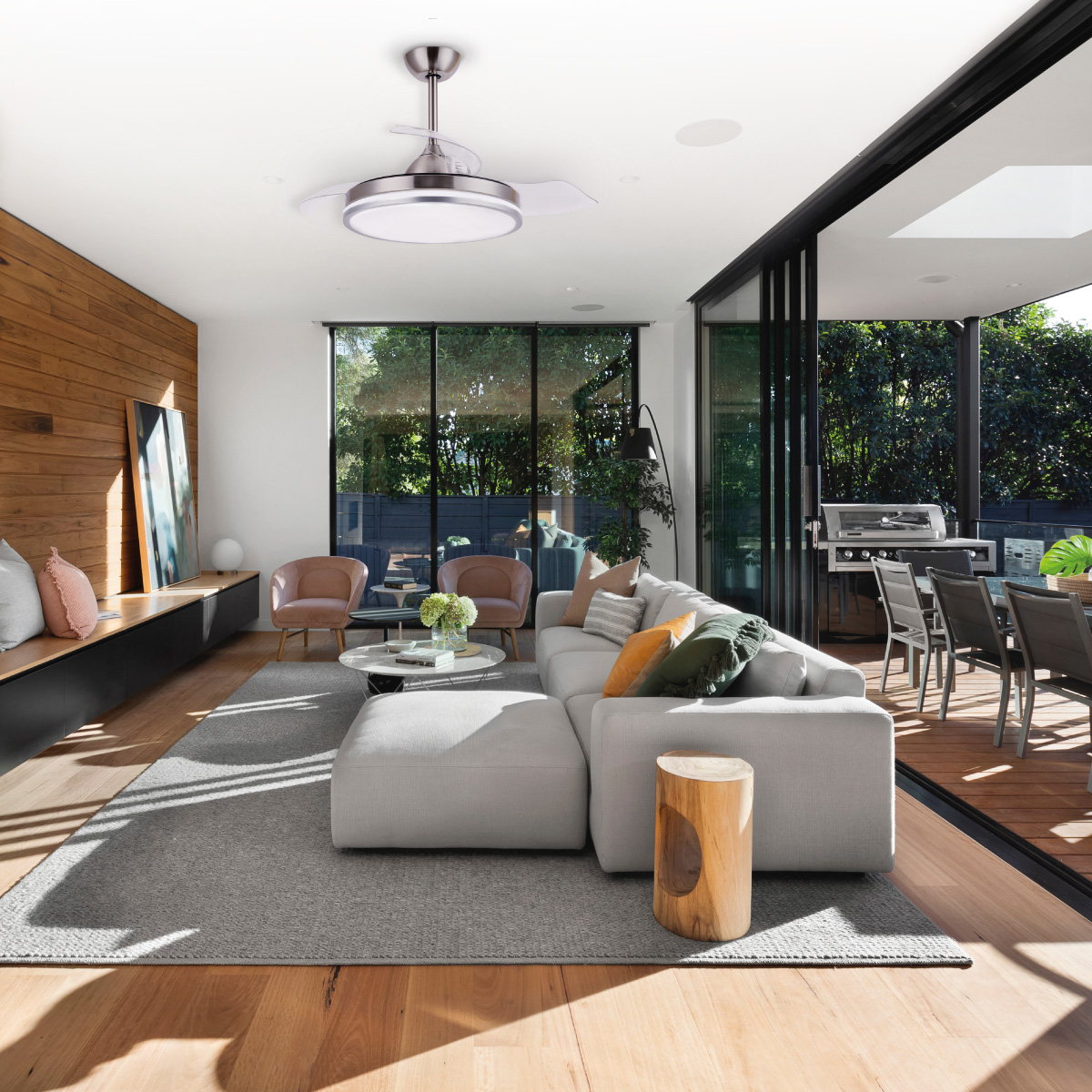 Salón moderno con sofá blanco, suelo de madera y ventanas grandes. Ventilador de techo instalado.