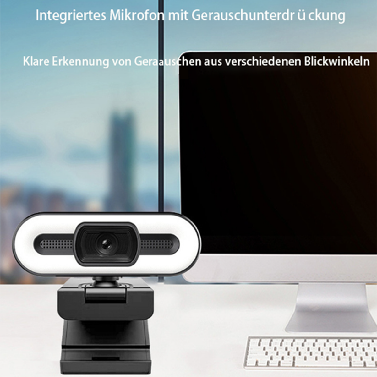 Eine Webcam mit deutschem Text auf einem Schreibtisch mit Computermonitor und Tastatur, schwarz-weißes Design.