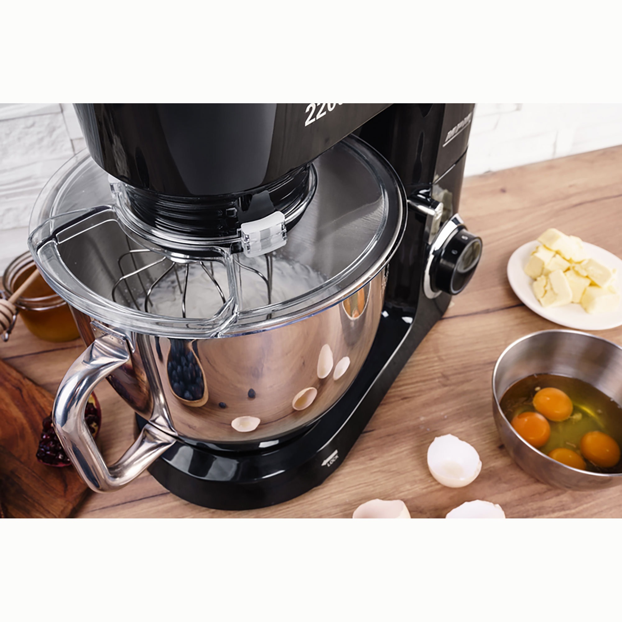 Schwarzer Küchenmixer mit Zutaten darin und drumherum. Holzoberfläche.