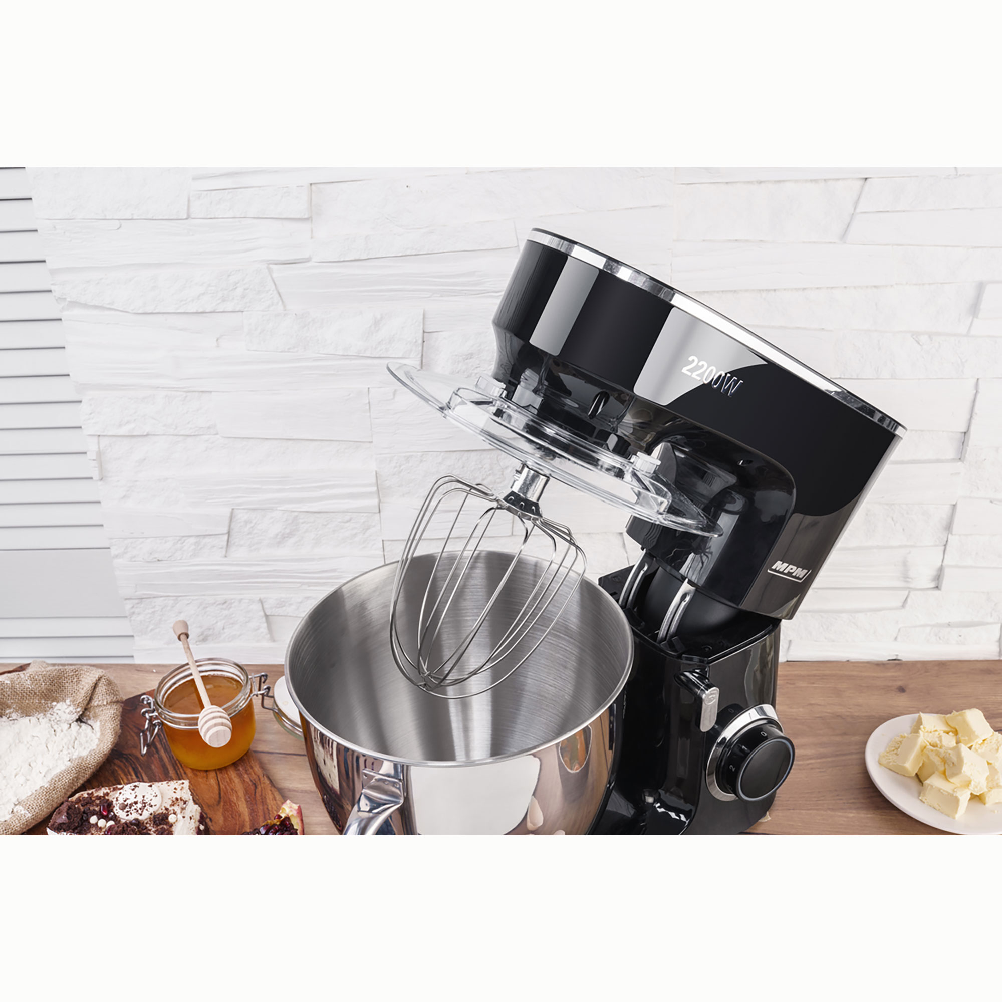 Schwarzer Küchenmixer mit silberner Schüssel, Mehl und Butter auf der Theke.