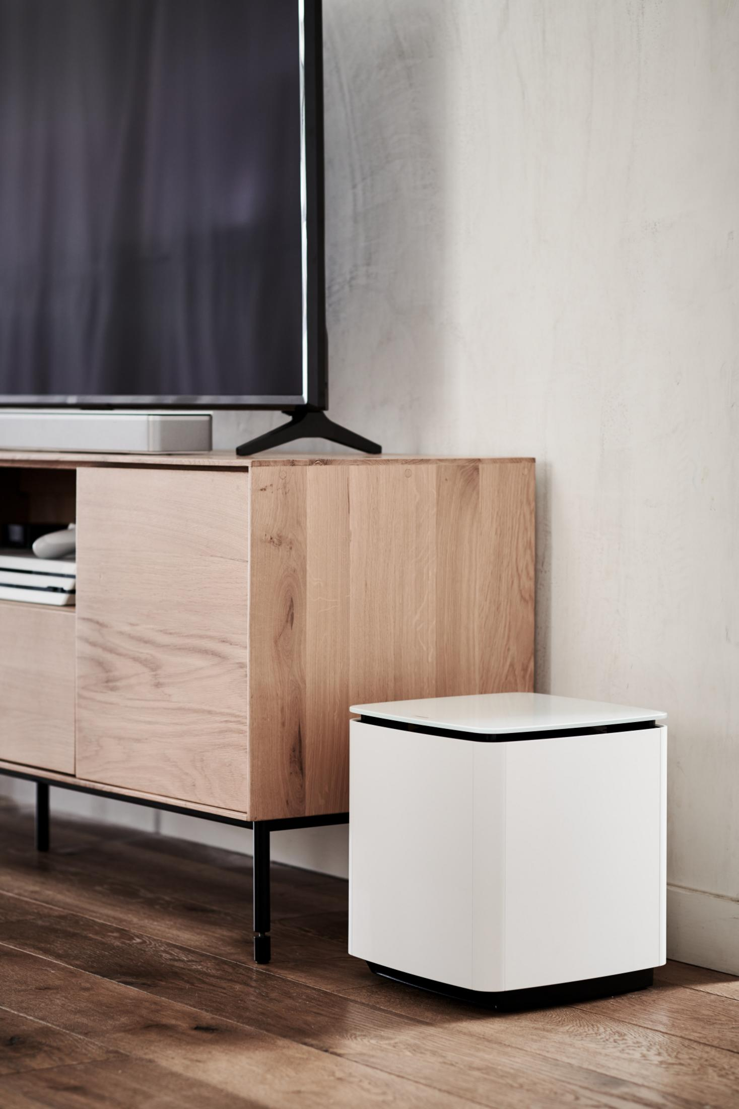 Wohnzimmerszene. Holzschrank mit Fernseher und weißem Subwoofer auf dem Boden.
