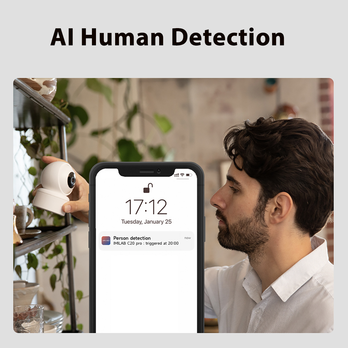 Ein Mann, der auf einen Telefonbildschirm schaut, mit einer Überwachungskamera im Hintergrund.