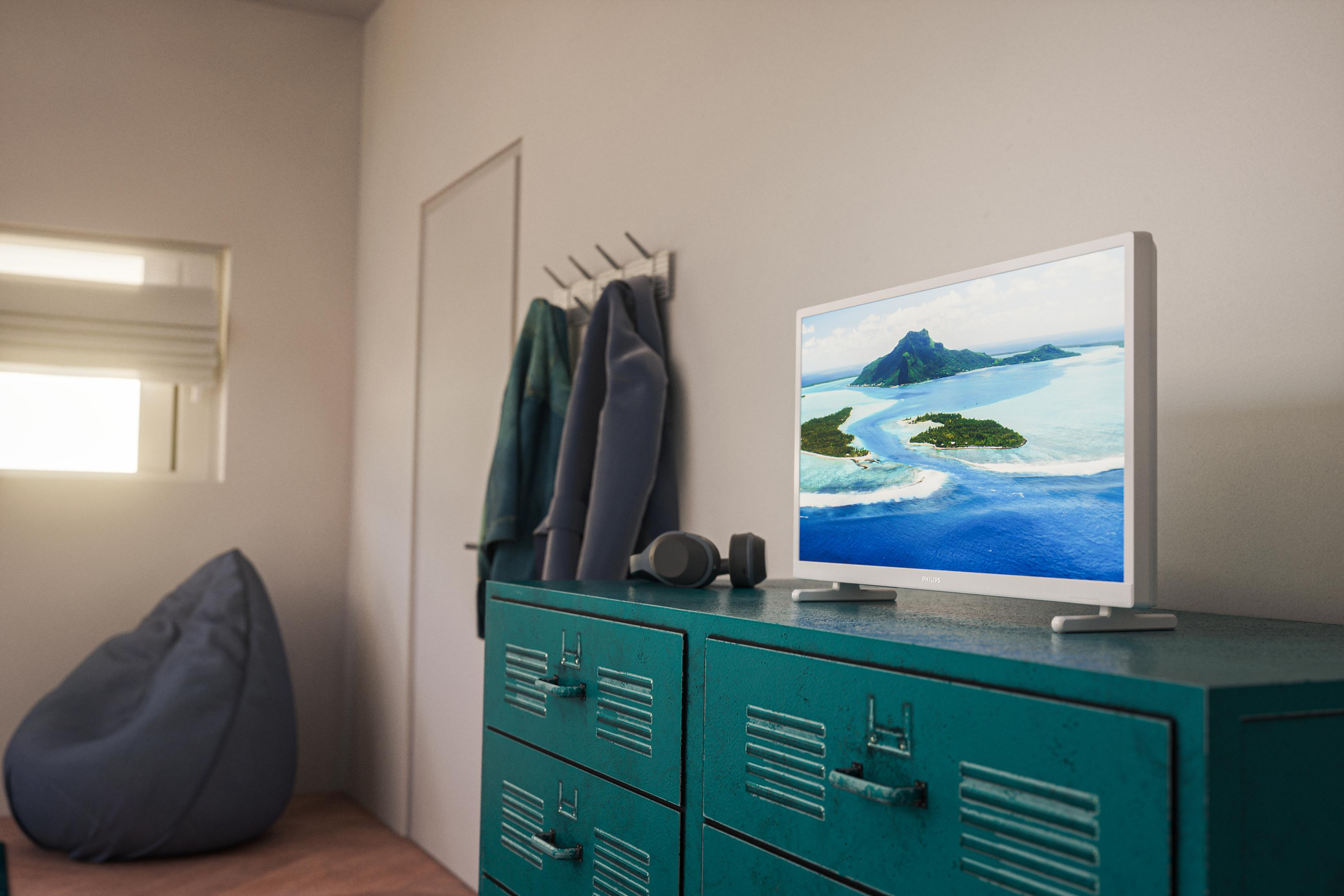 Wnętrze pokoju z telewizorem na turkusowej komodzie. Widoczny worek sako i drzwi.