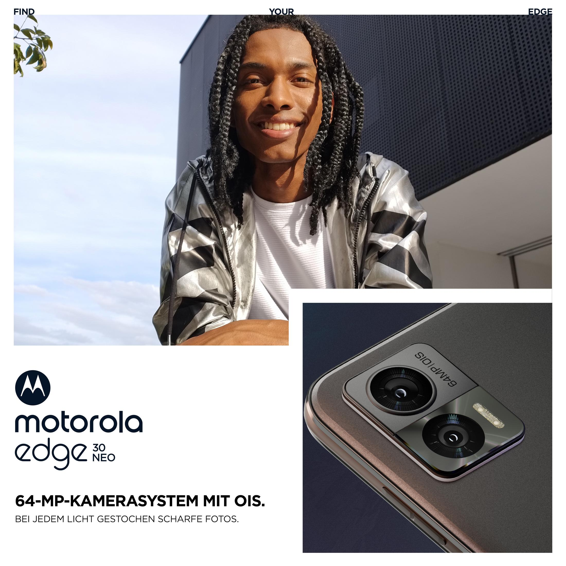 Een man met dreadlocks glimlacht, houdt een telefoon vast, met een close-up van de camera.