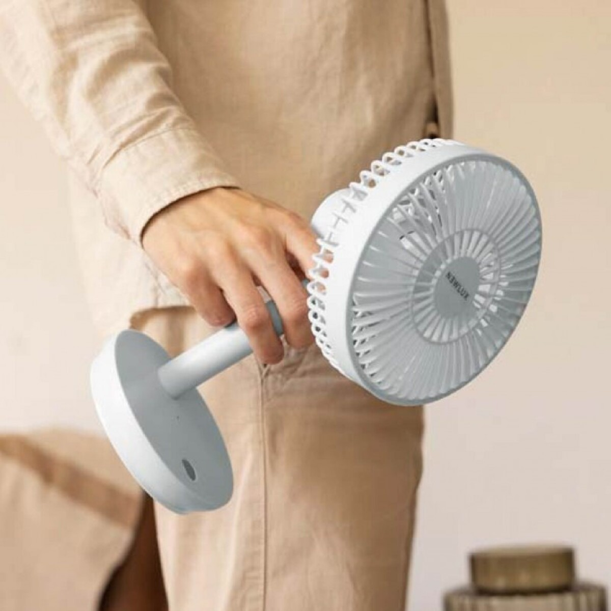 Persona sosteniendo un ventilador portátil blanco y gris.