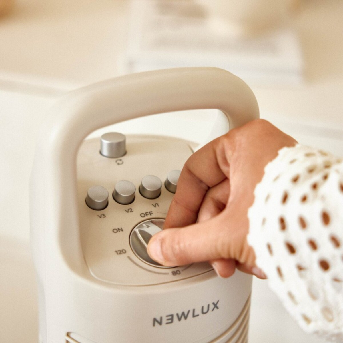 La mano de una persona ajustando el dial de un electrodoméstico beige y blanco.