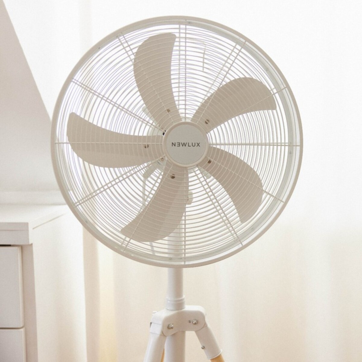 Un ventilador de pie blanco. Tiene una cabeza circular y una base de trípode.