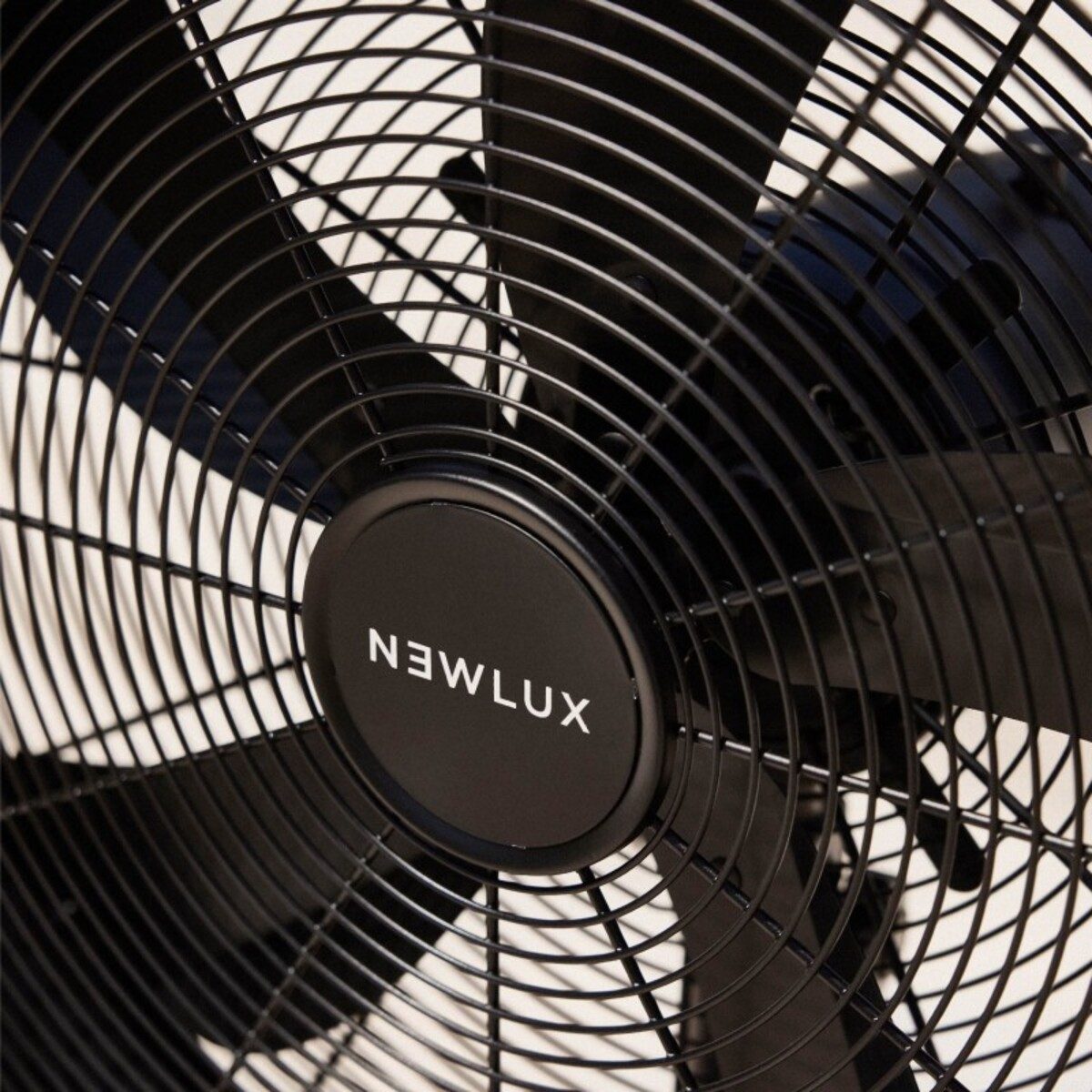 Primer plano de un ventilador negro con la marca NEWLUX visible en el centro.