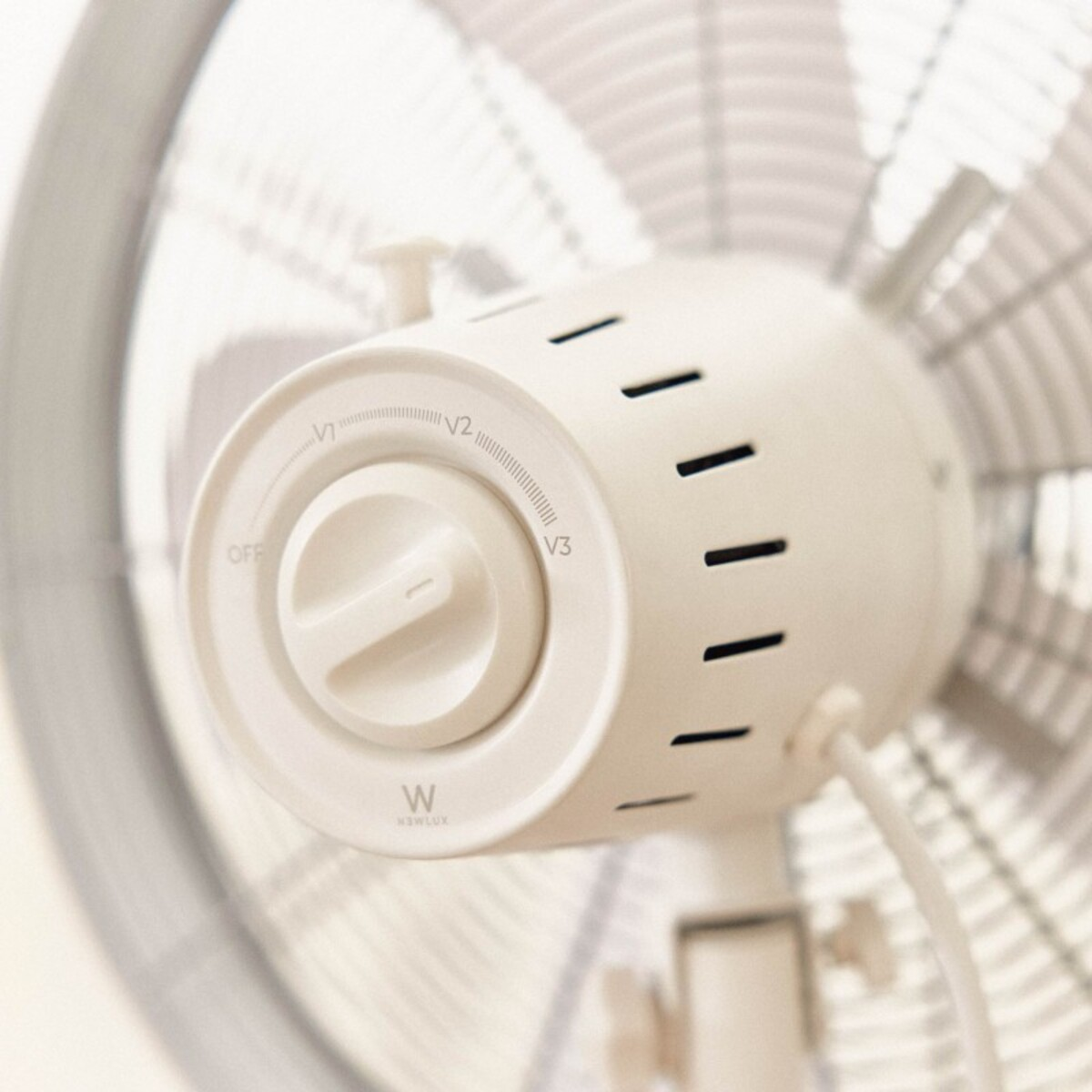 Primer plano del panel de control de un ventilador blanco. Tiene un dial con ajustes de velocidad.