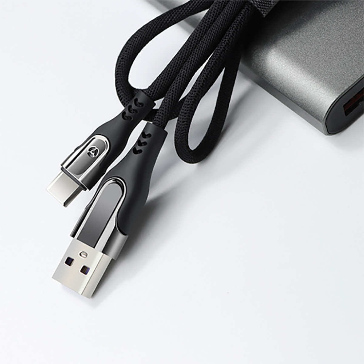 Schwarzes USB-Ladekabel mit USB-A- und USB-C-Anschlüssen, auf weißer Oberfläche platziert.