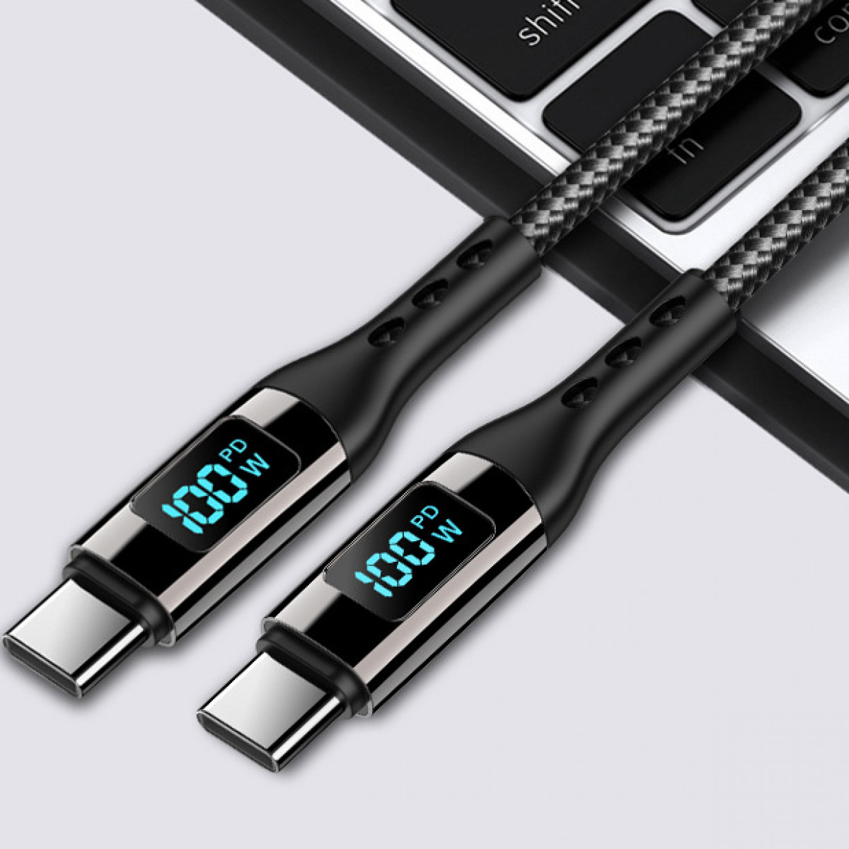 Zwei schwarze USB-C-Ladekabel mit blauem Display, das 100W anzeigt, auf verschwommenem Hintergrund.